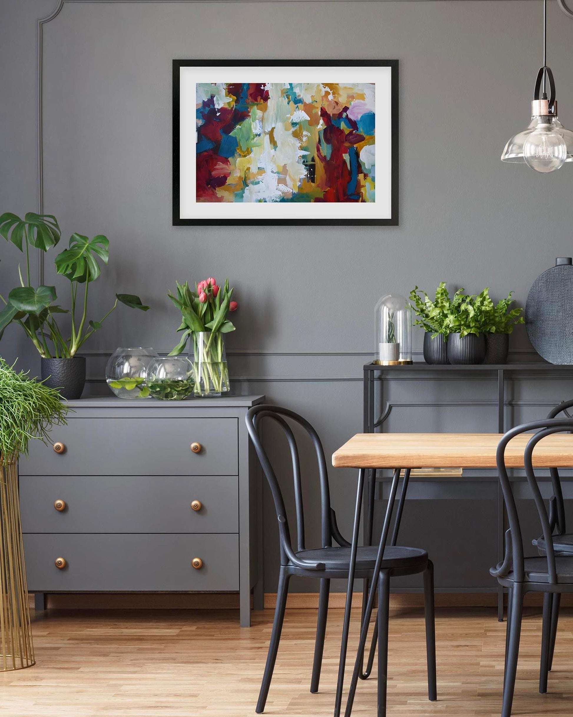 Dining room with a gray wall, colorful abstract painting, and a wooden table.