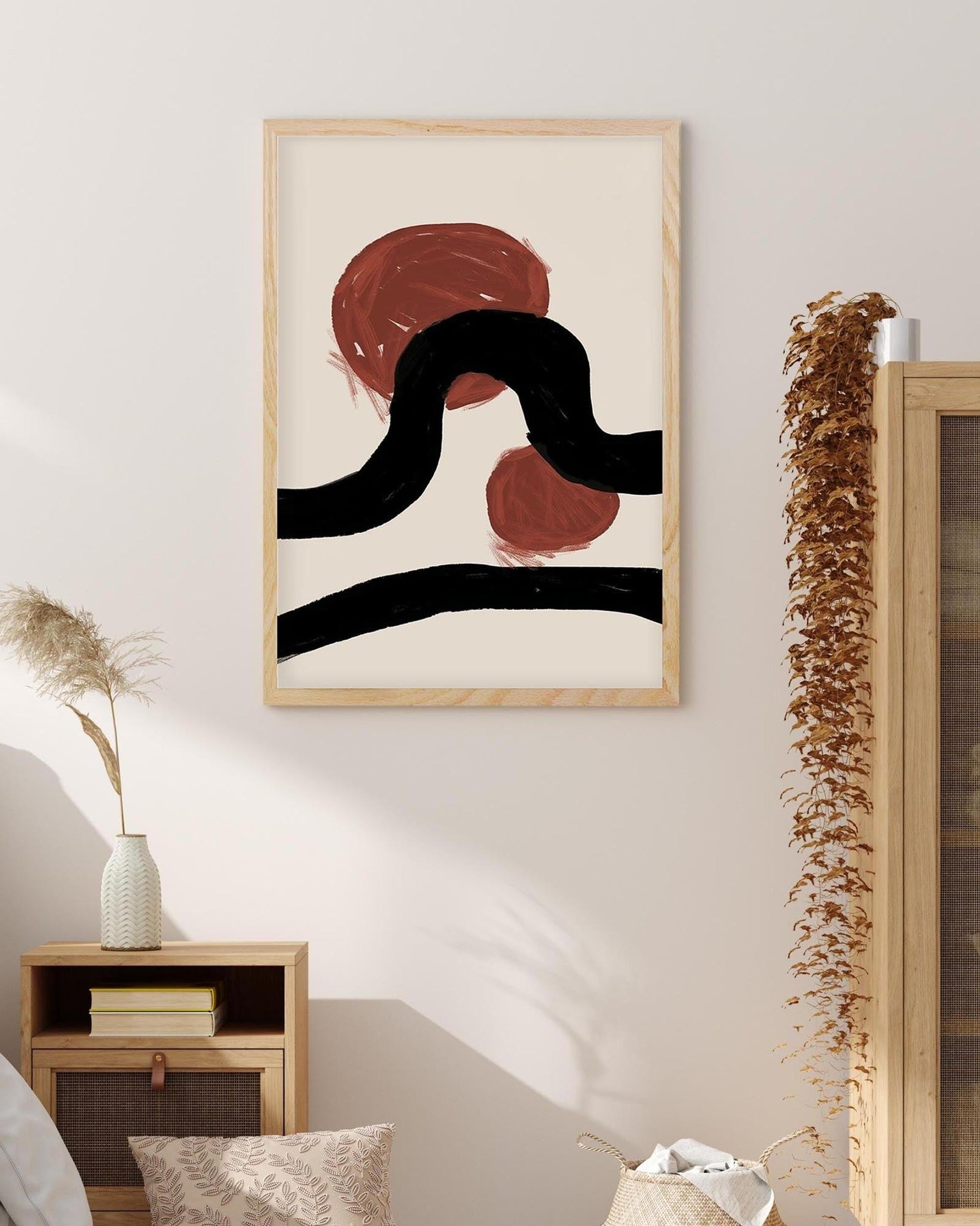 Abstract art print with black and red shapes in a wooden frame on a wall.