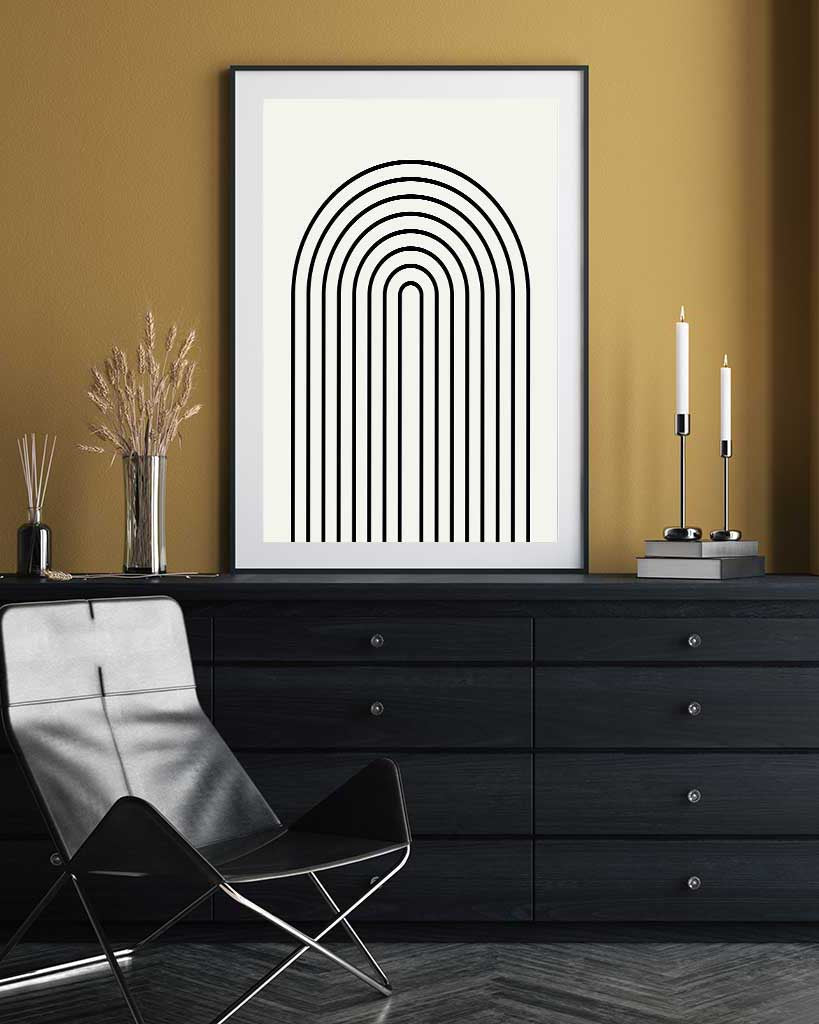 Framed abstract art print on a wall above a black dresser with decorative items.