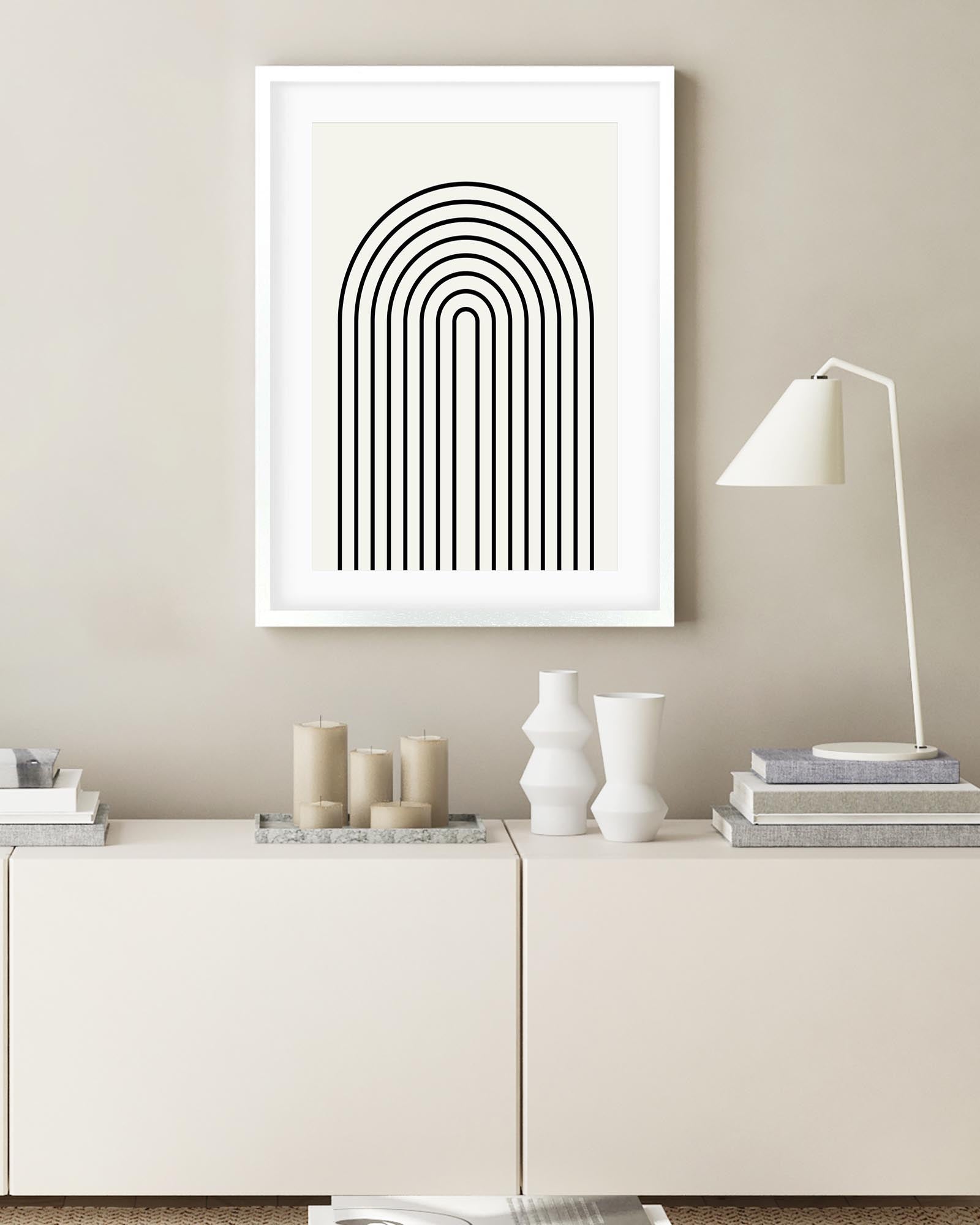 Framed abstract art print on a wall above a white cabinet with decorative items.