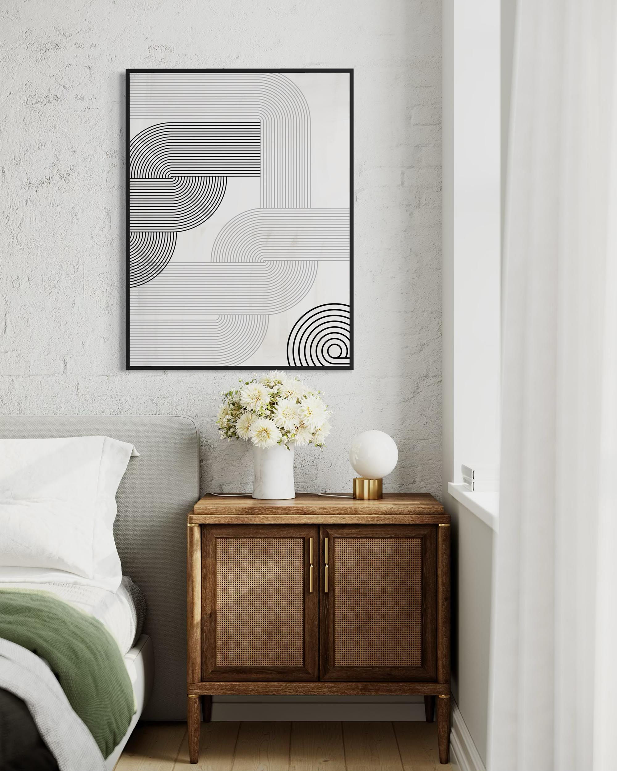 Modern bedroom with abstract art, wooden side table, and white flowers.