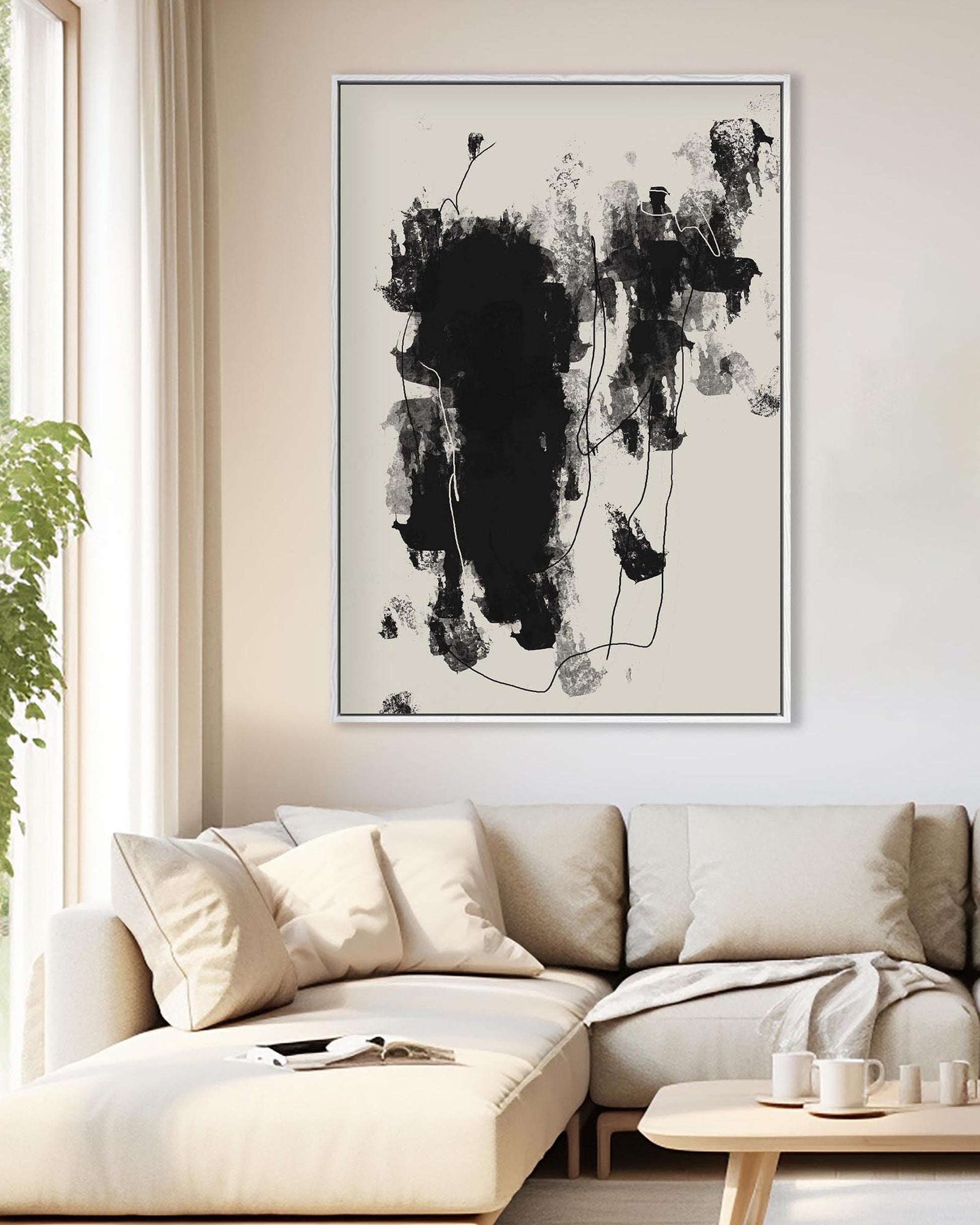 Abstract black and white painting on a wall above a beige sofa in a living room.