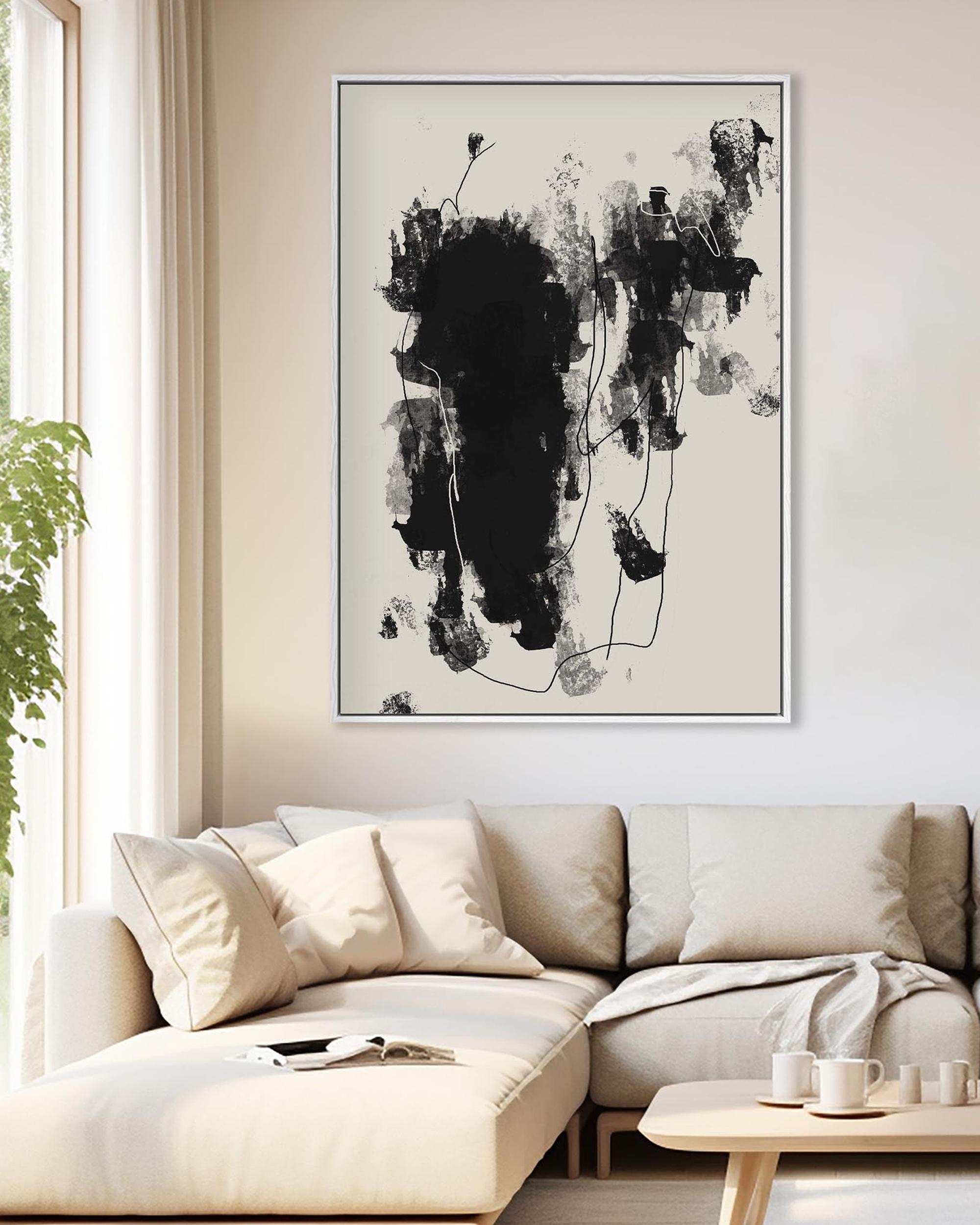 Abstract black and white painting on a wall above a beige sofa in a living room.