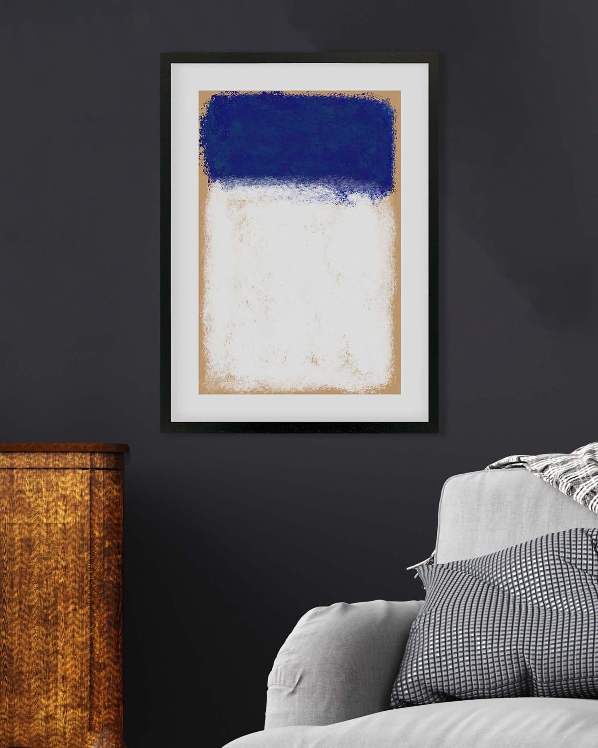 Abstract art print with blue and white colors on a dark wall above a sofa.