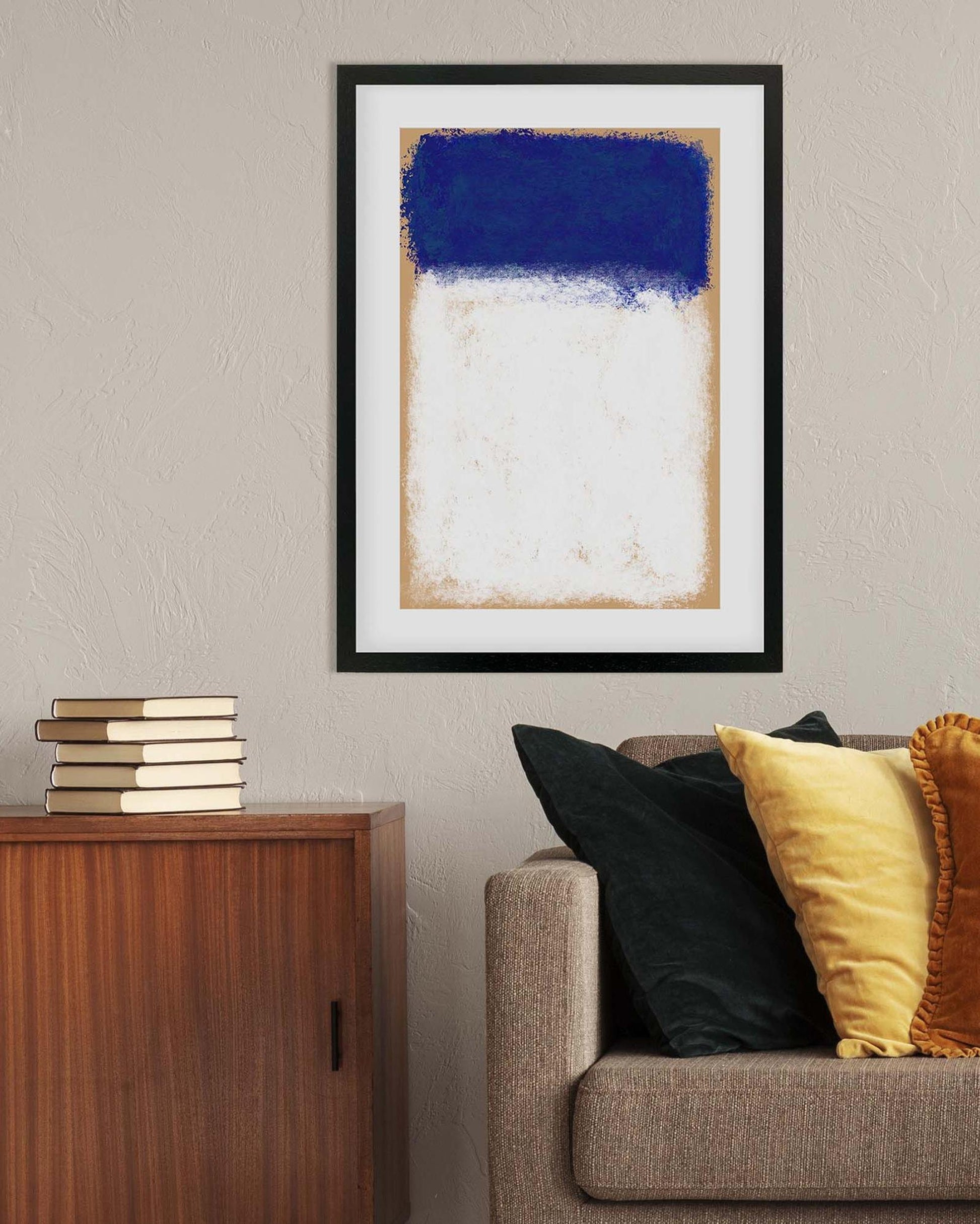Framed abstract art piece on a wall above a sofa with decorative pillows.