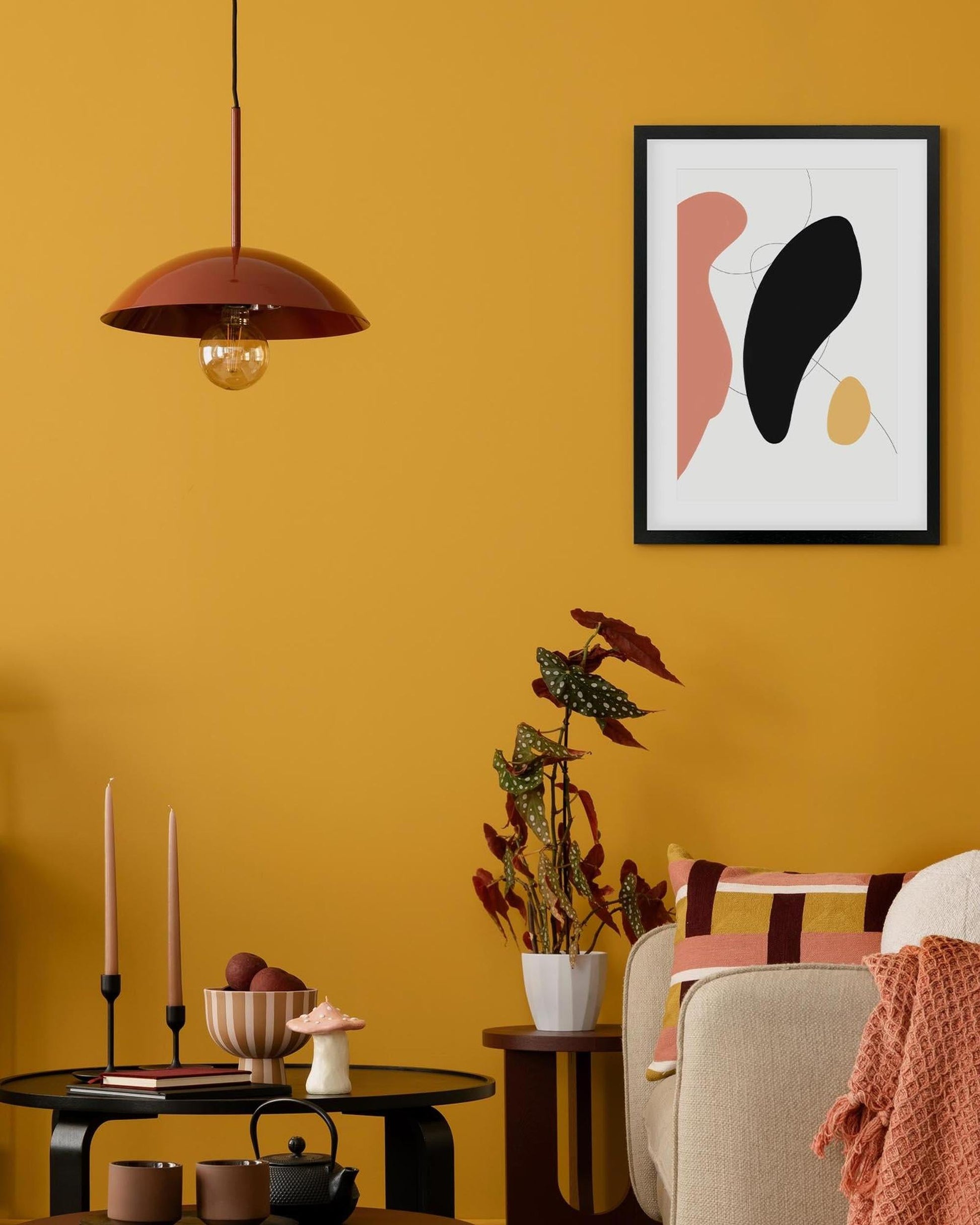 Living room with mustard yellow walls, abstract art, and decorative items.