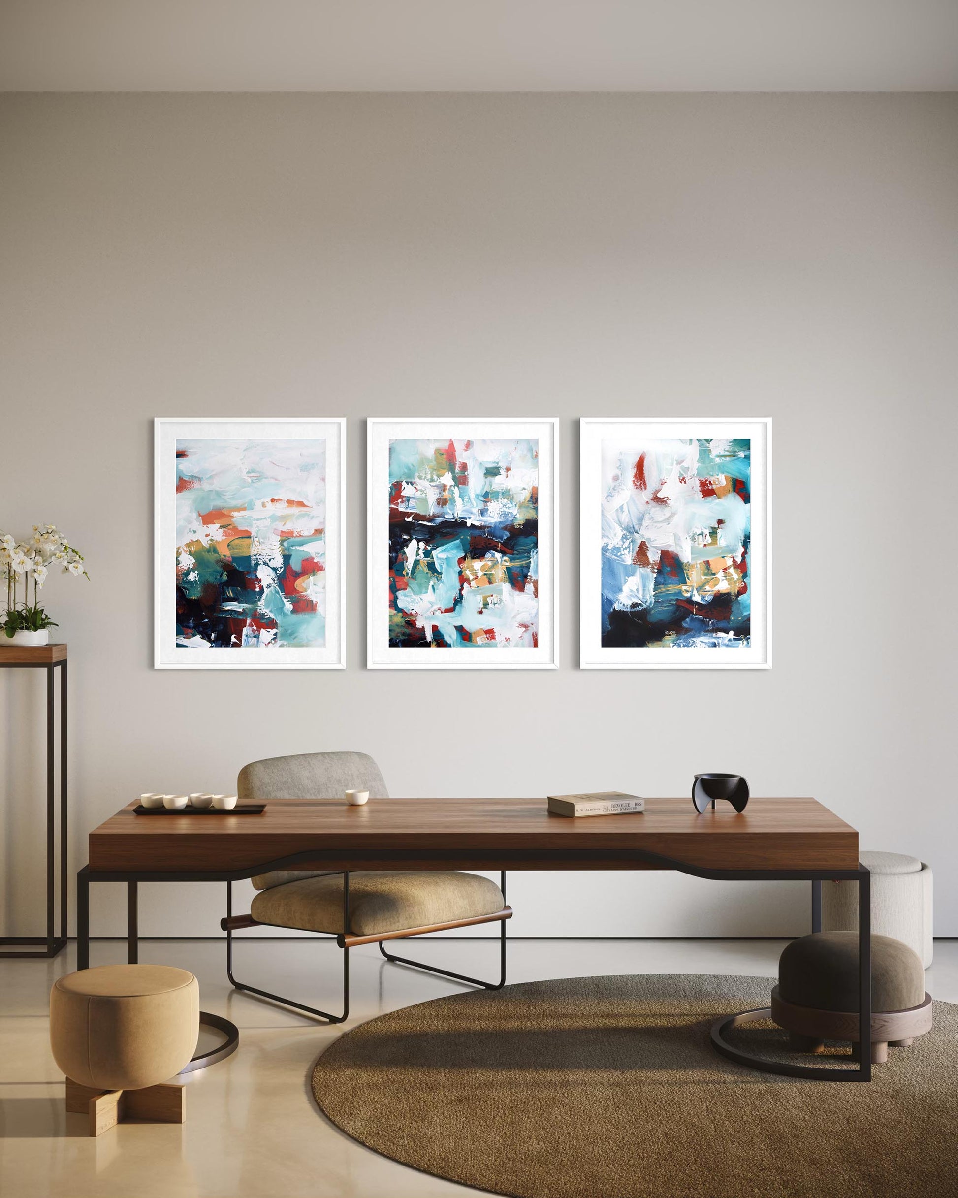 Three abstract paintings on a wall above a wooden desk in a modern room.