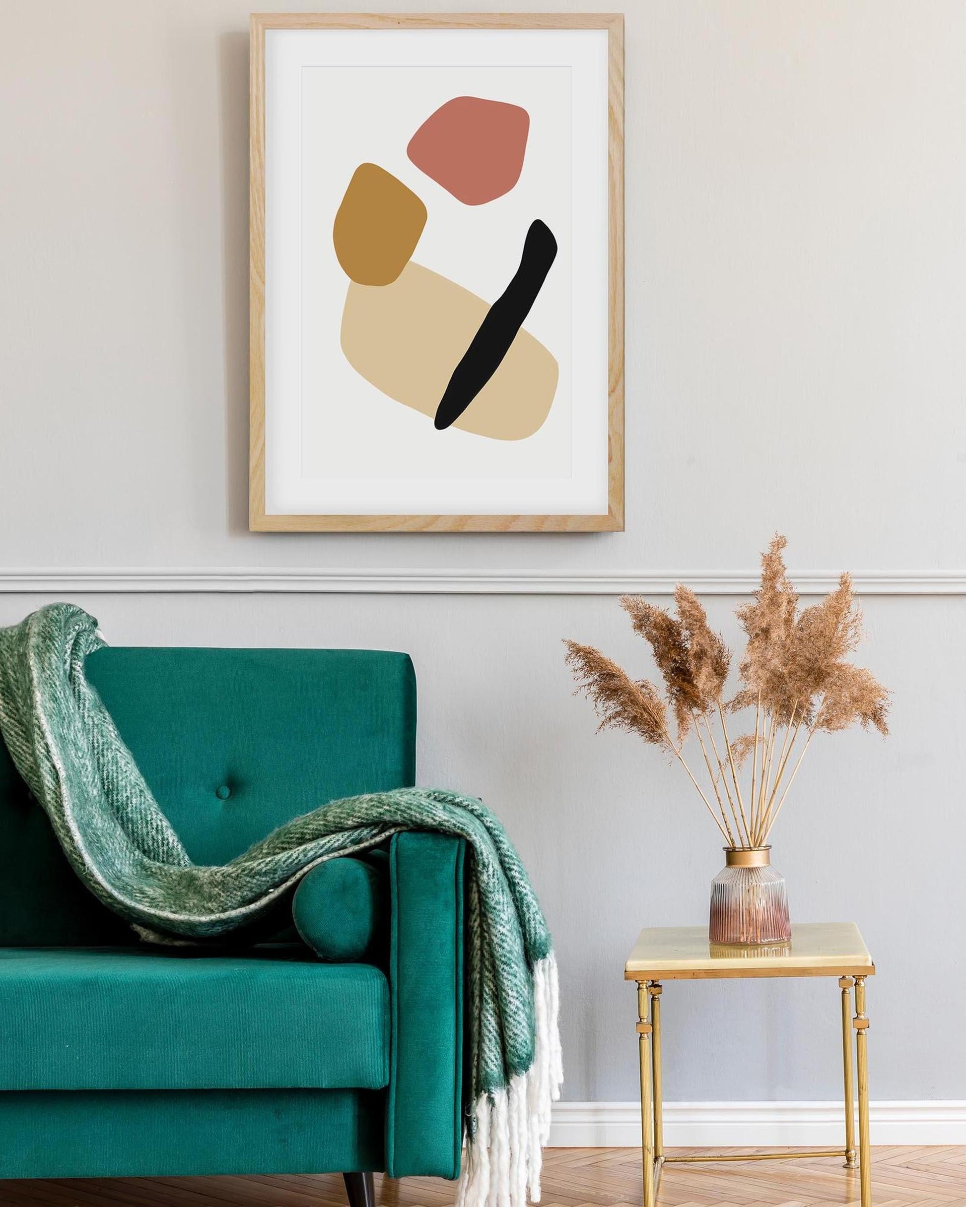 Abstract art print on a wall above a teal chair with a green blanket.