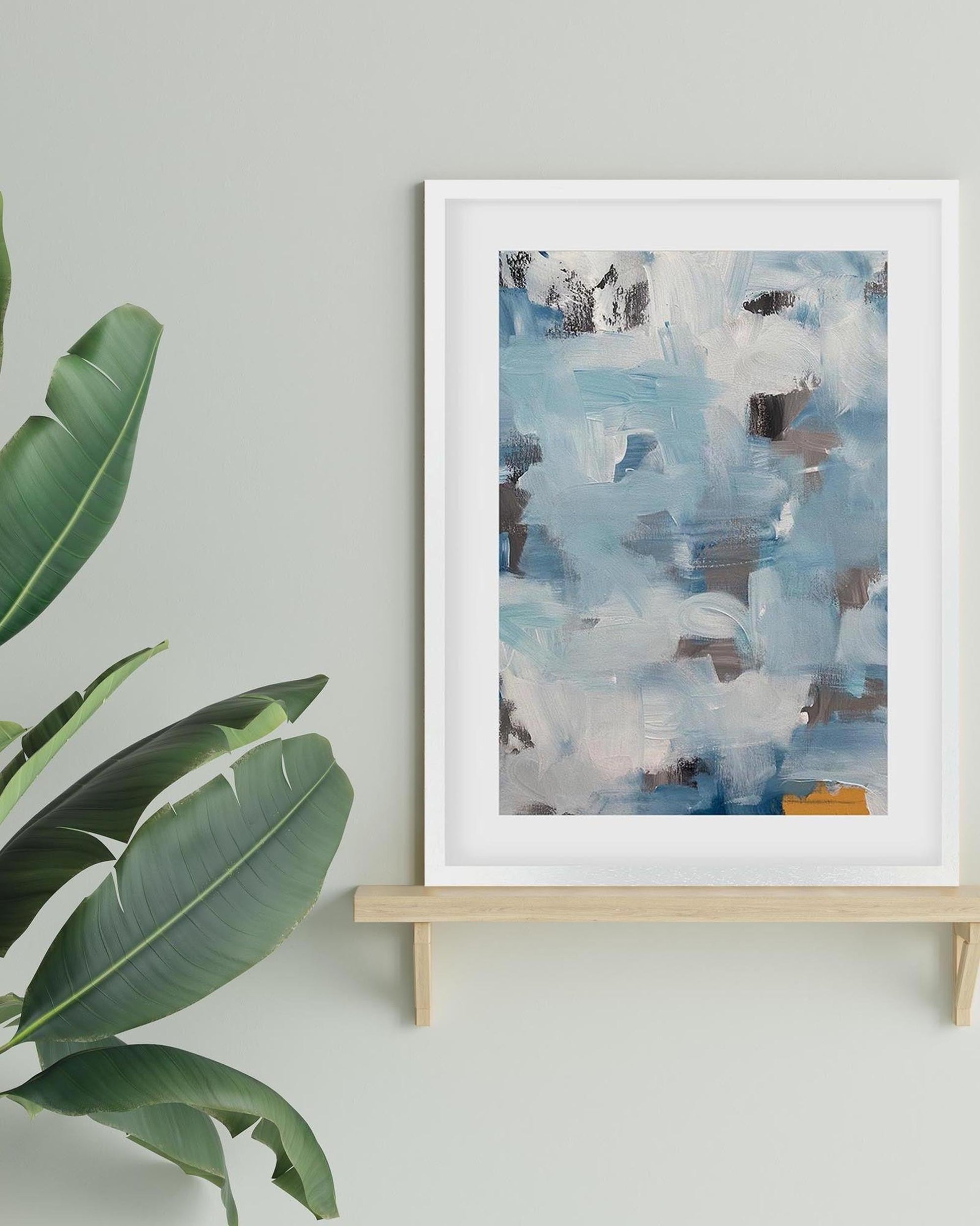 Abstract art print on a stand with a plant to the left against a light gray wall