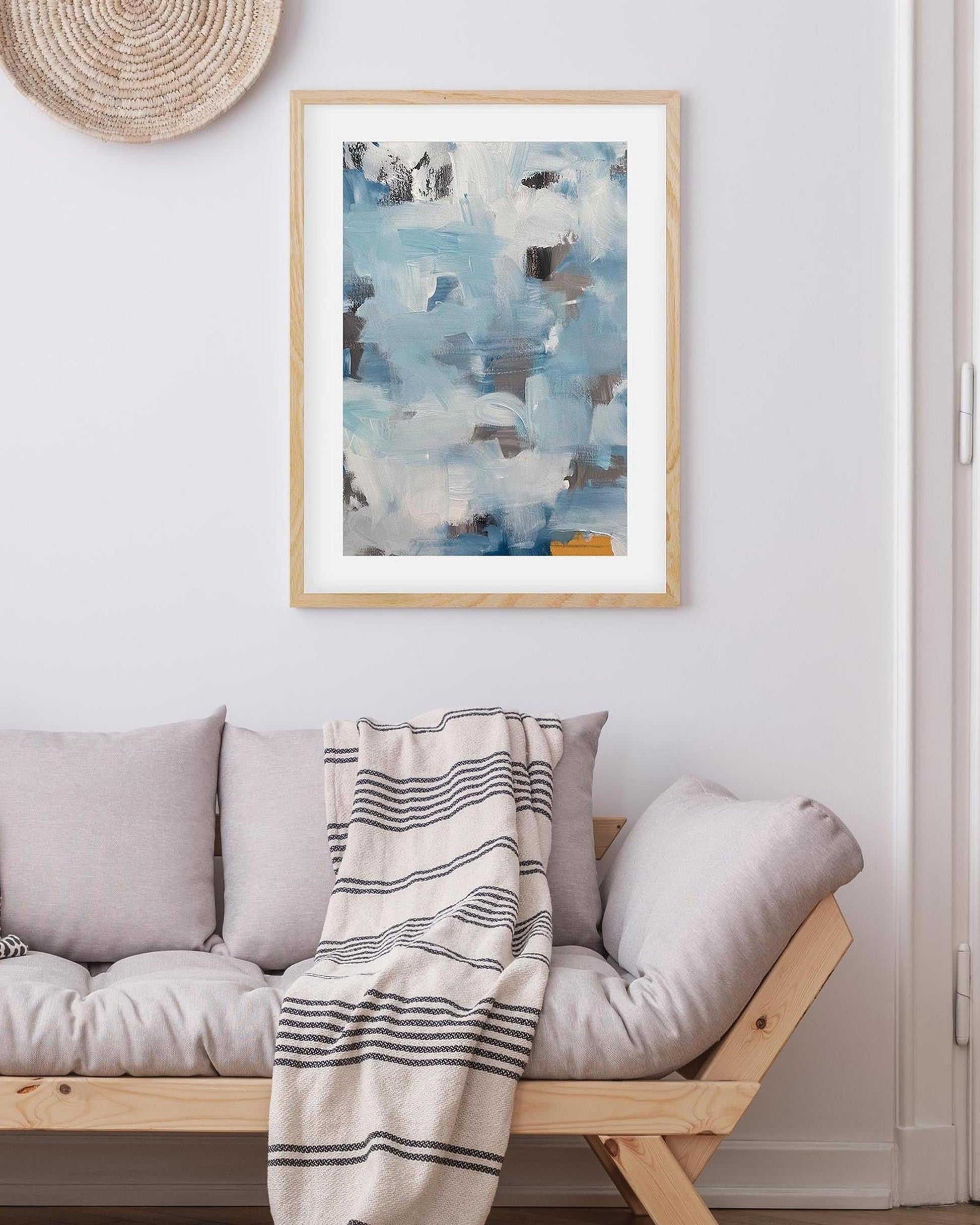 Framed abstract art above a sofa with a striped blanket