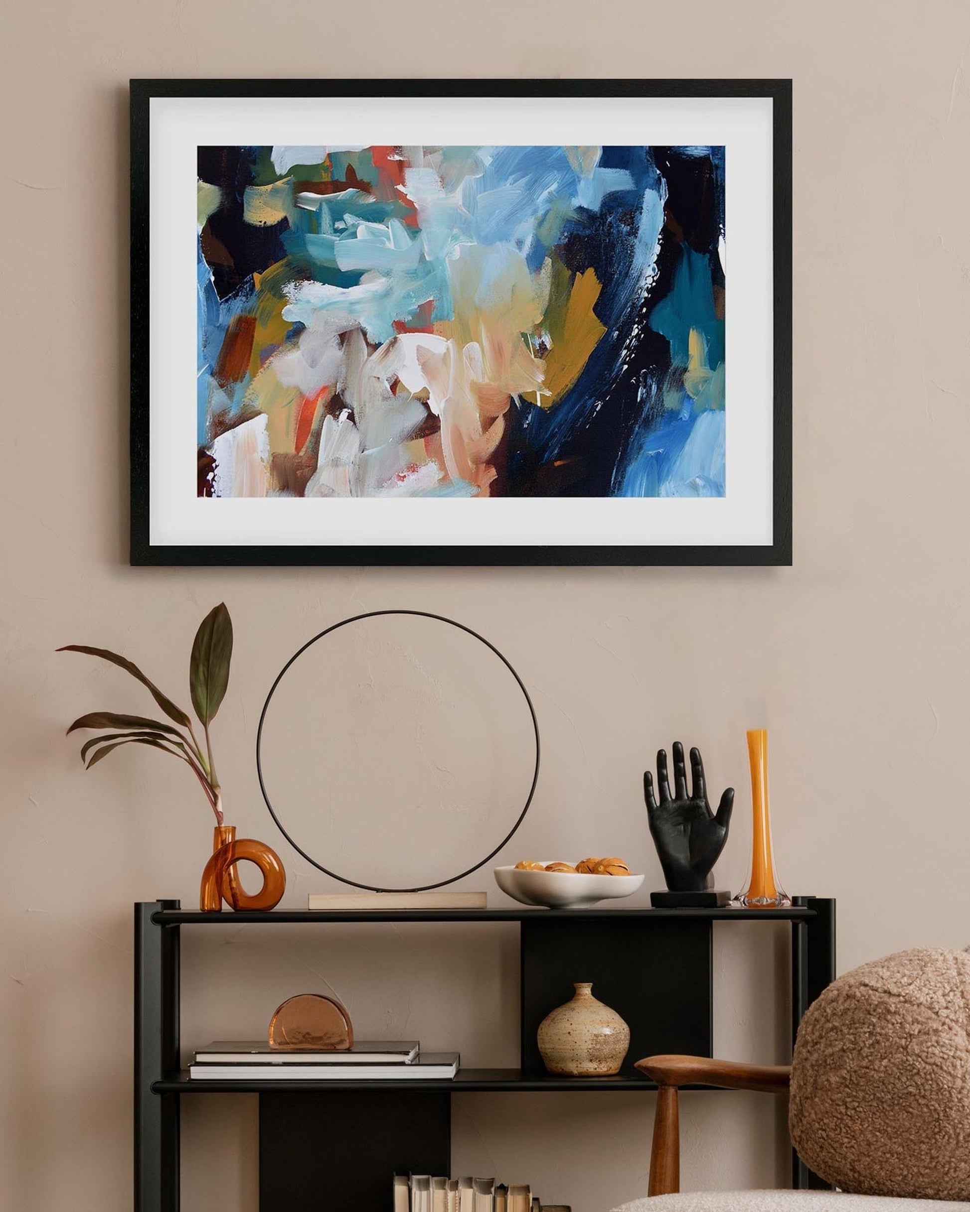Abstract painting on a wall above a shelf with decorative items.