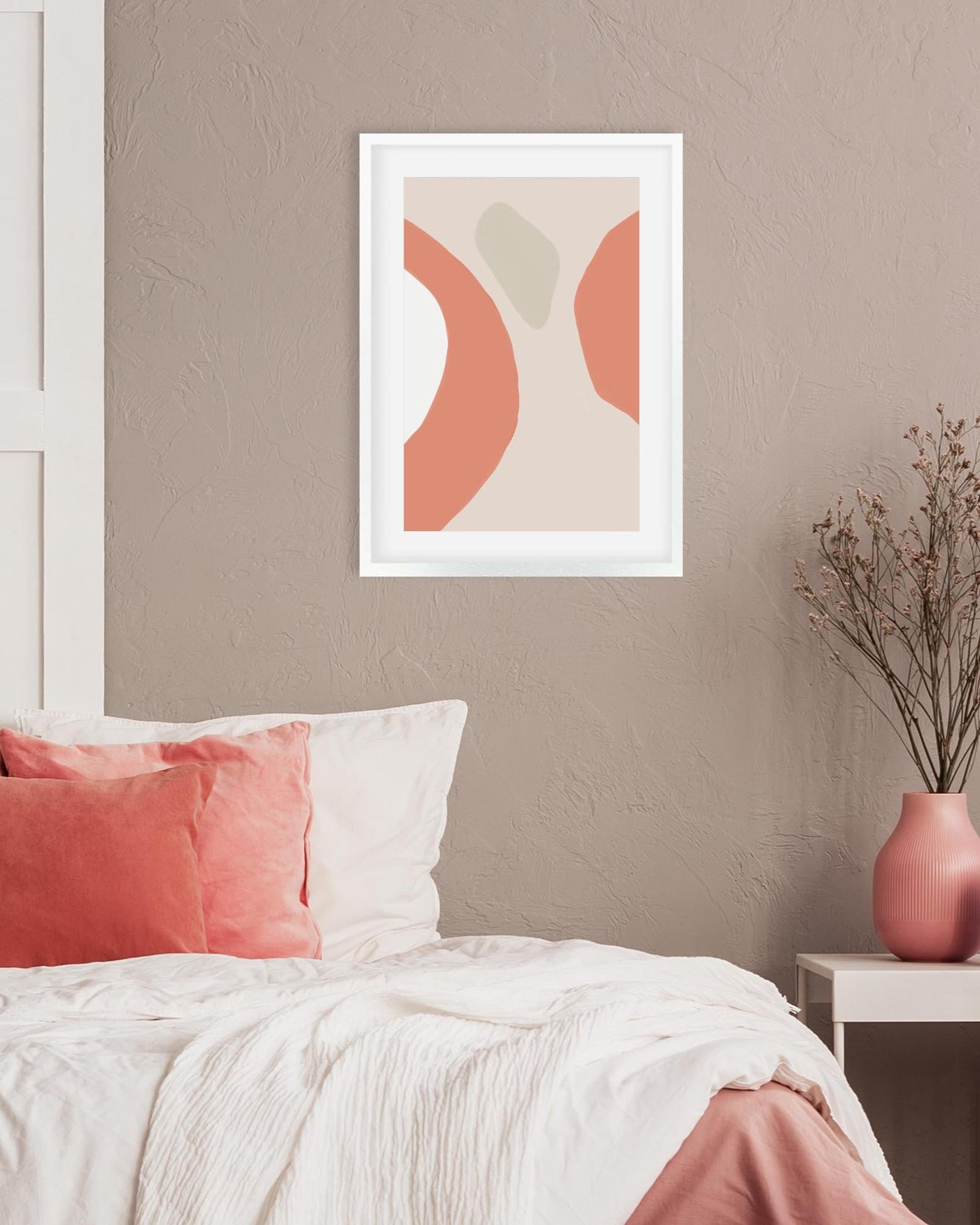 Framed abstract art print on a wall above a bed with pink and white bedding.