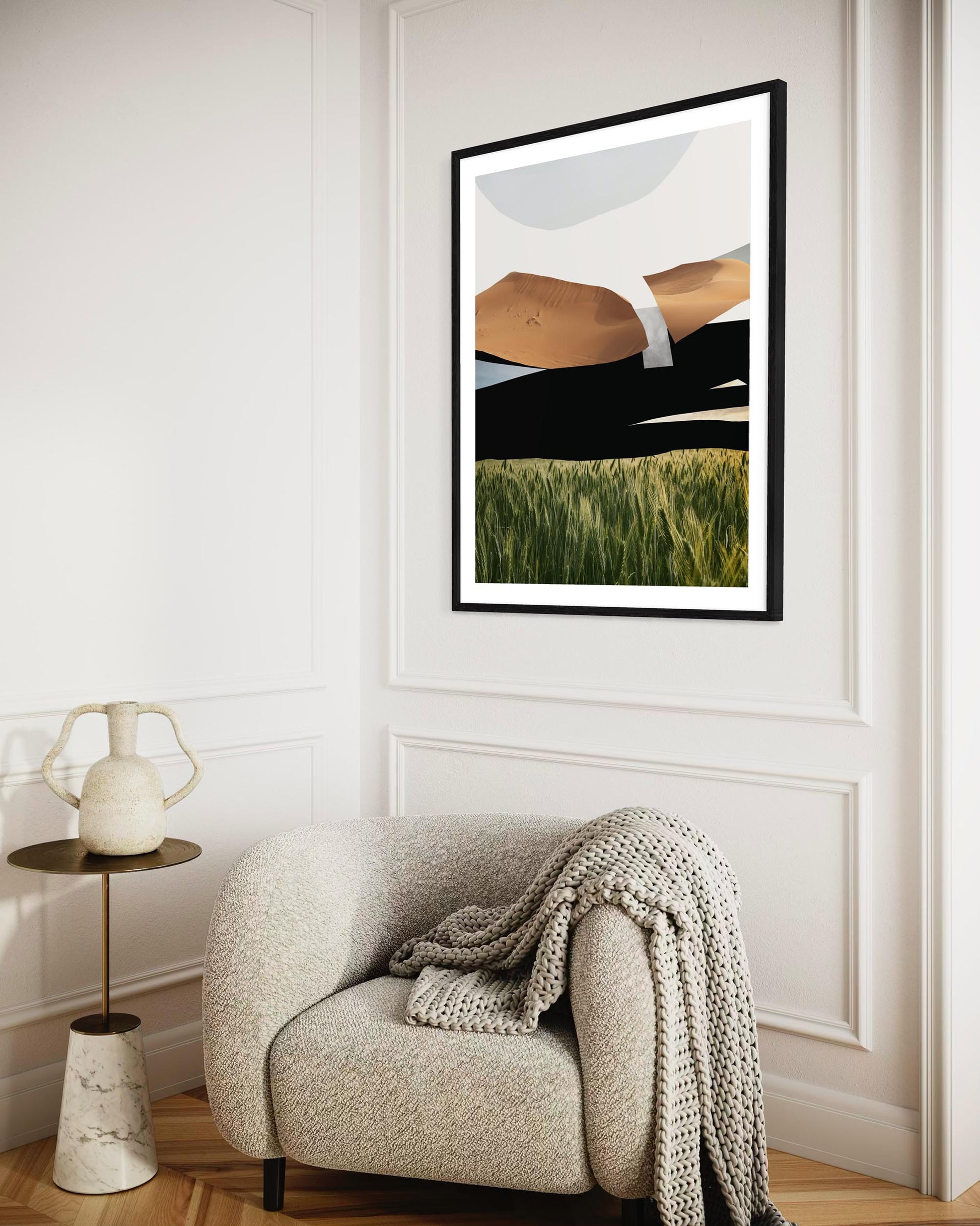 Framed abstract art on a wall above a cozy armchair with a blanket.