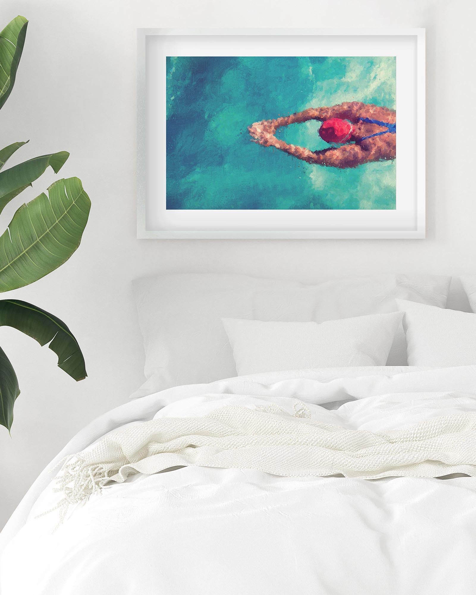 Framed artwork of a person swimming in a pool on a wall above a bed.
