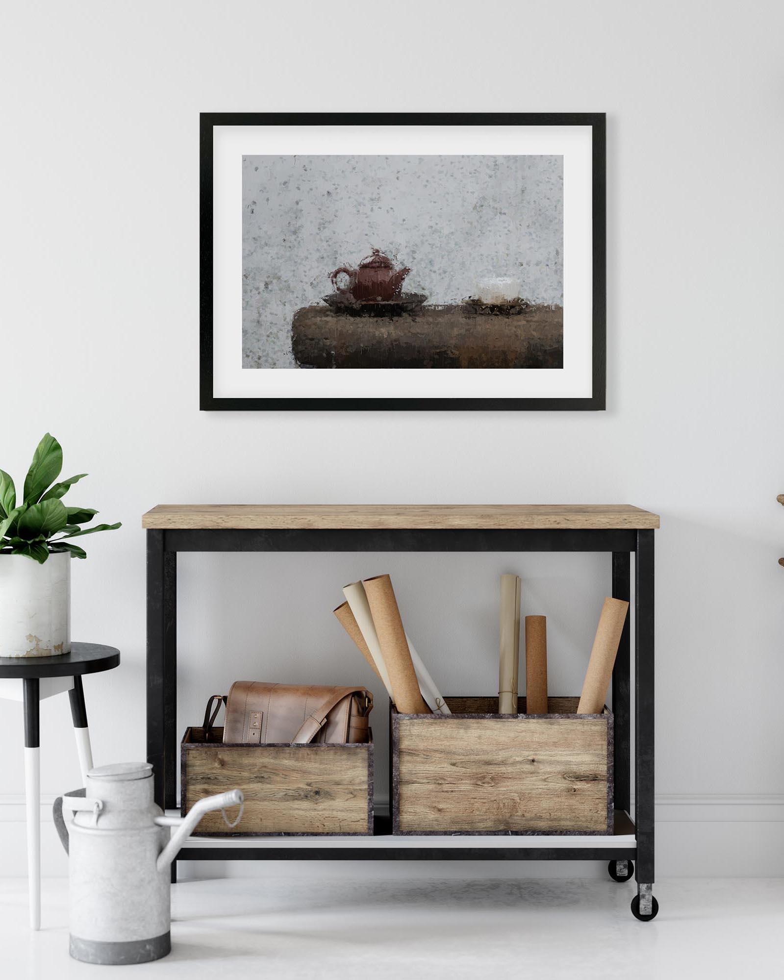 Framed artwork of a teapot on a stone surface above a wooden console table with storage boxes.