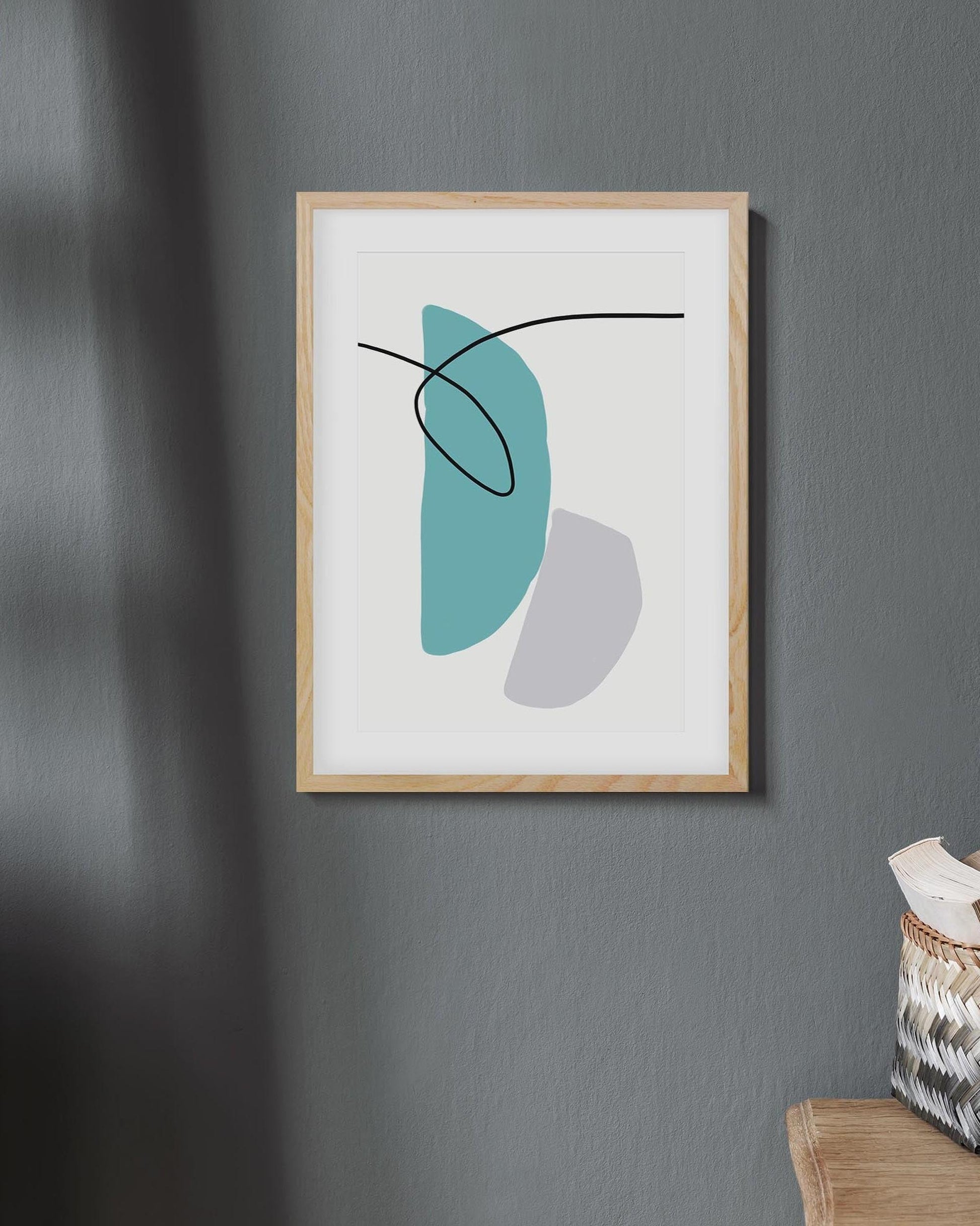 Framed abstract art print with geometric shapes on a gray wall.