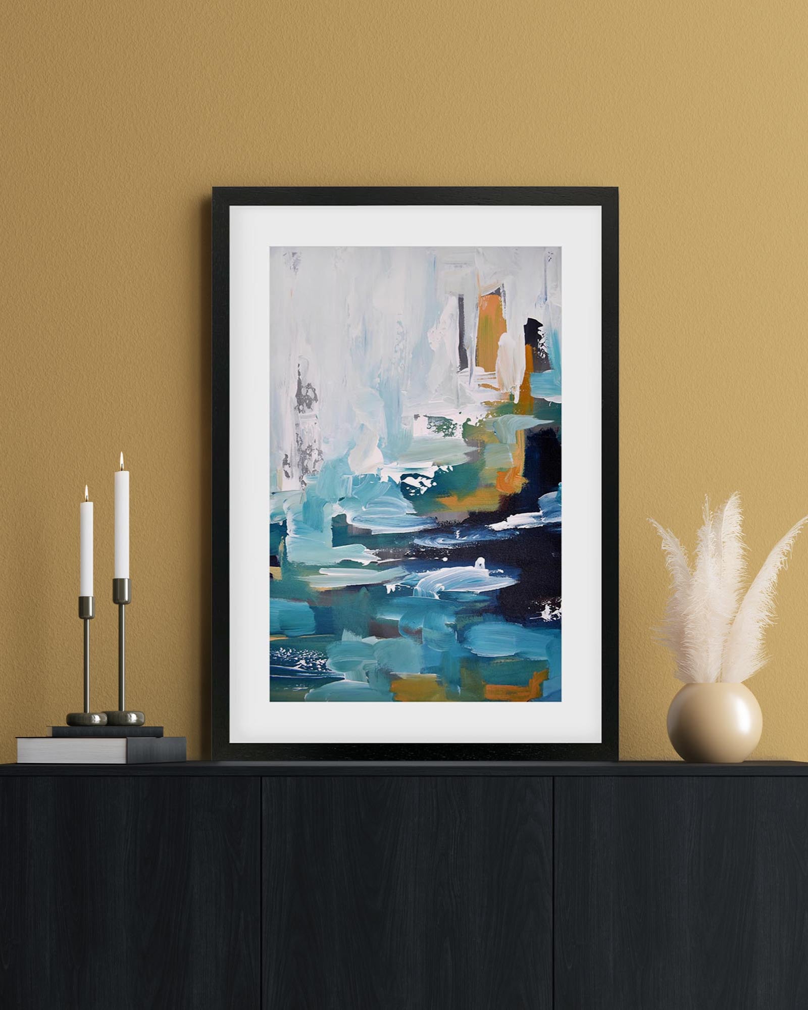 Framed abstract art print on a wall above a black cabinet with decorative items.