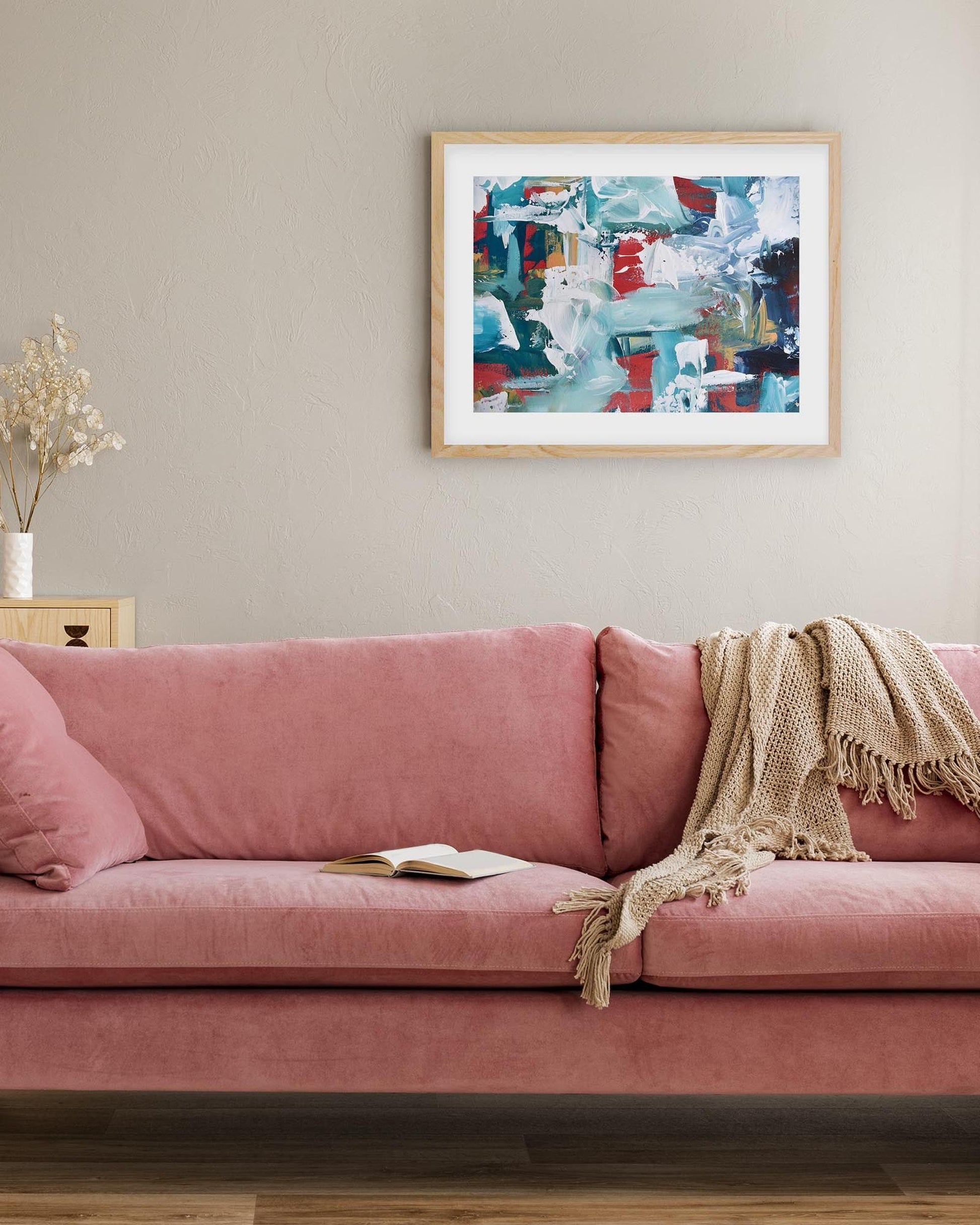 Pink sofa in a living room with a colorful abstract painting on the wall.