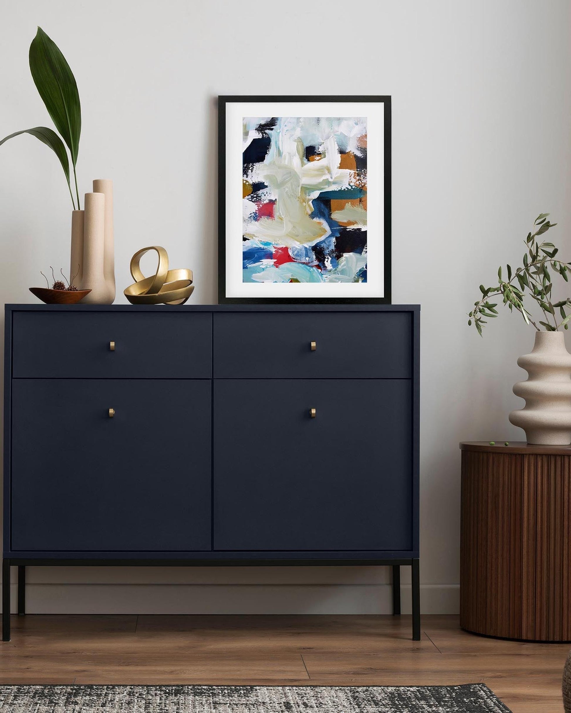 Navy blue cabinet with decorative items and a colorful abstract painting on a white wall.