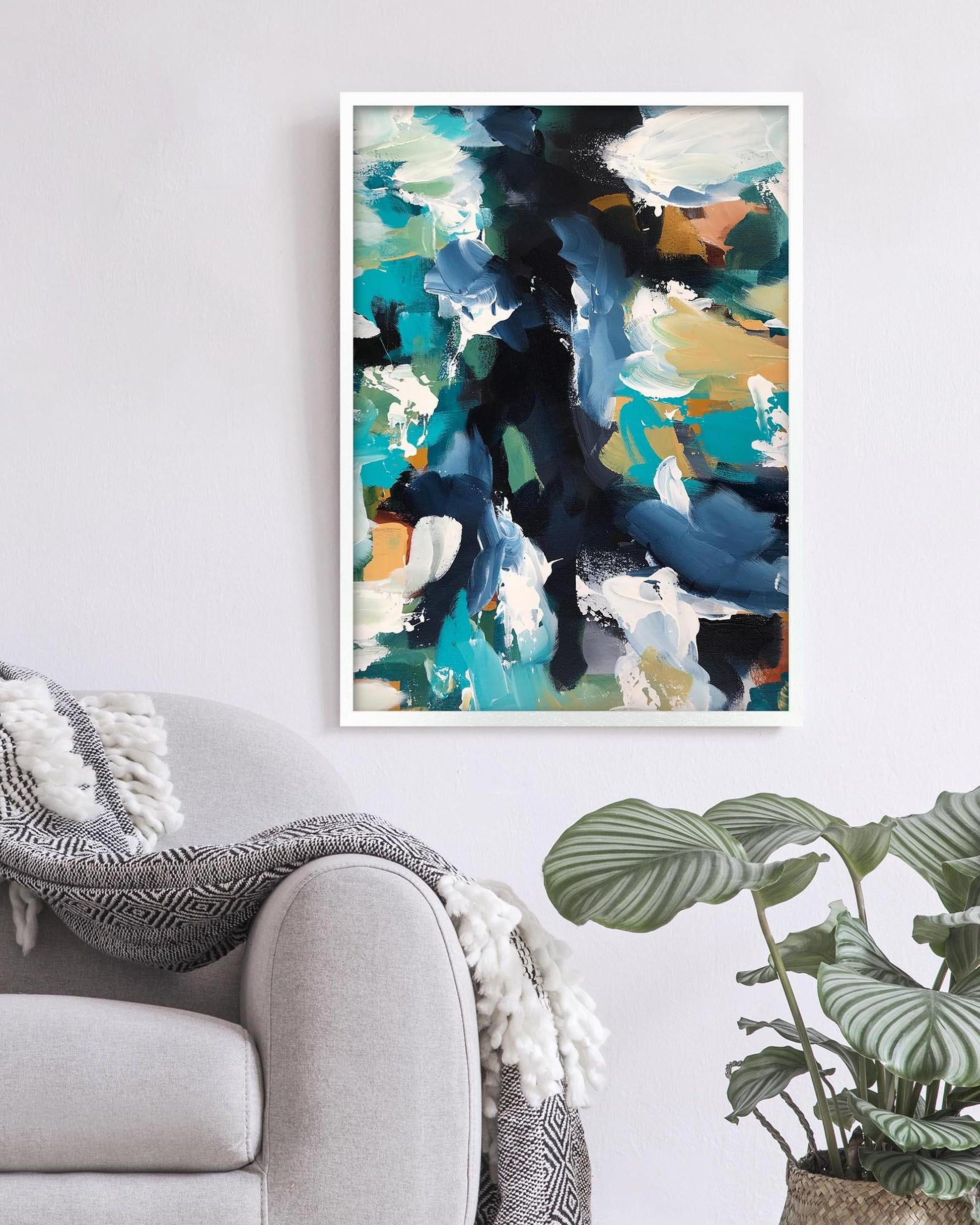 Abstract art print on a wall above a sofa with a plant in the corner