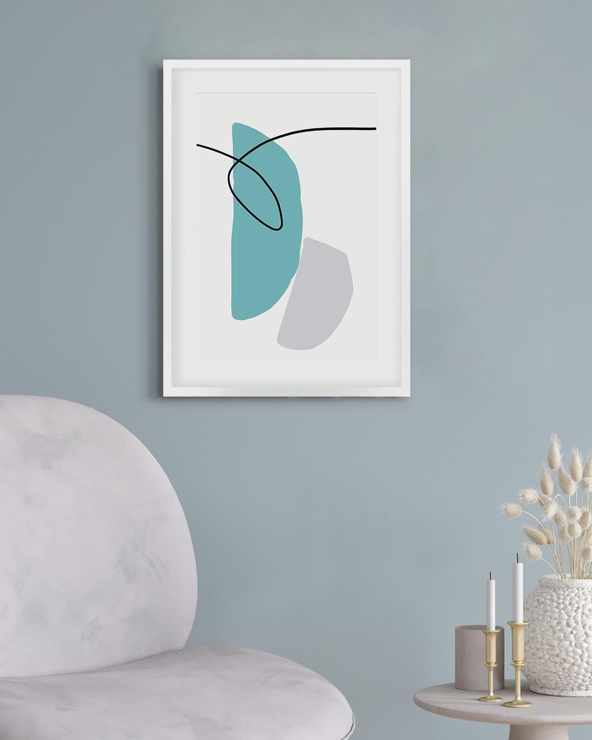 Abstract art print with blue and gray shapes in a white frame on a light blue wall.