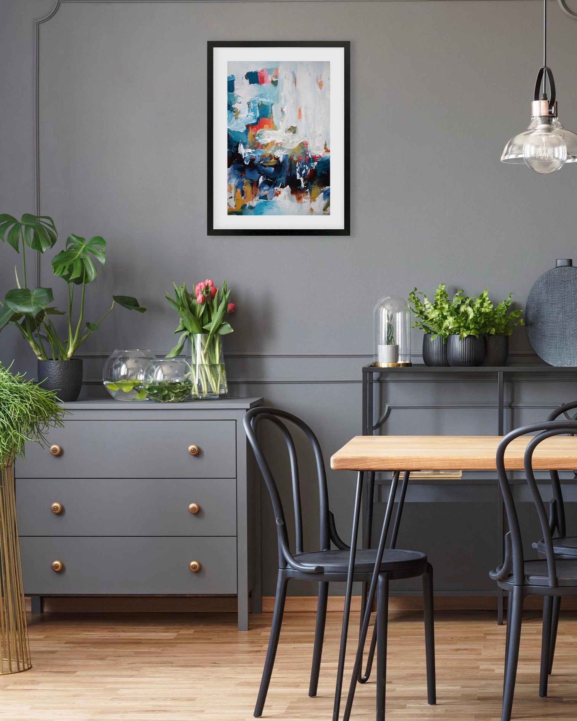 Dining room with gray walls, a wooden table, black chairs, and decorative elements.
