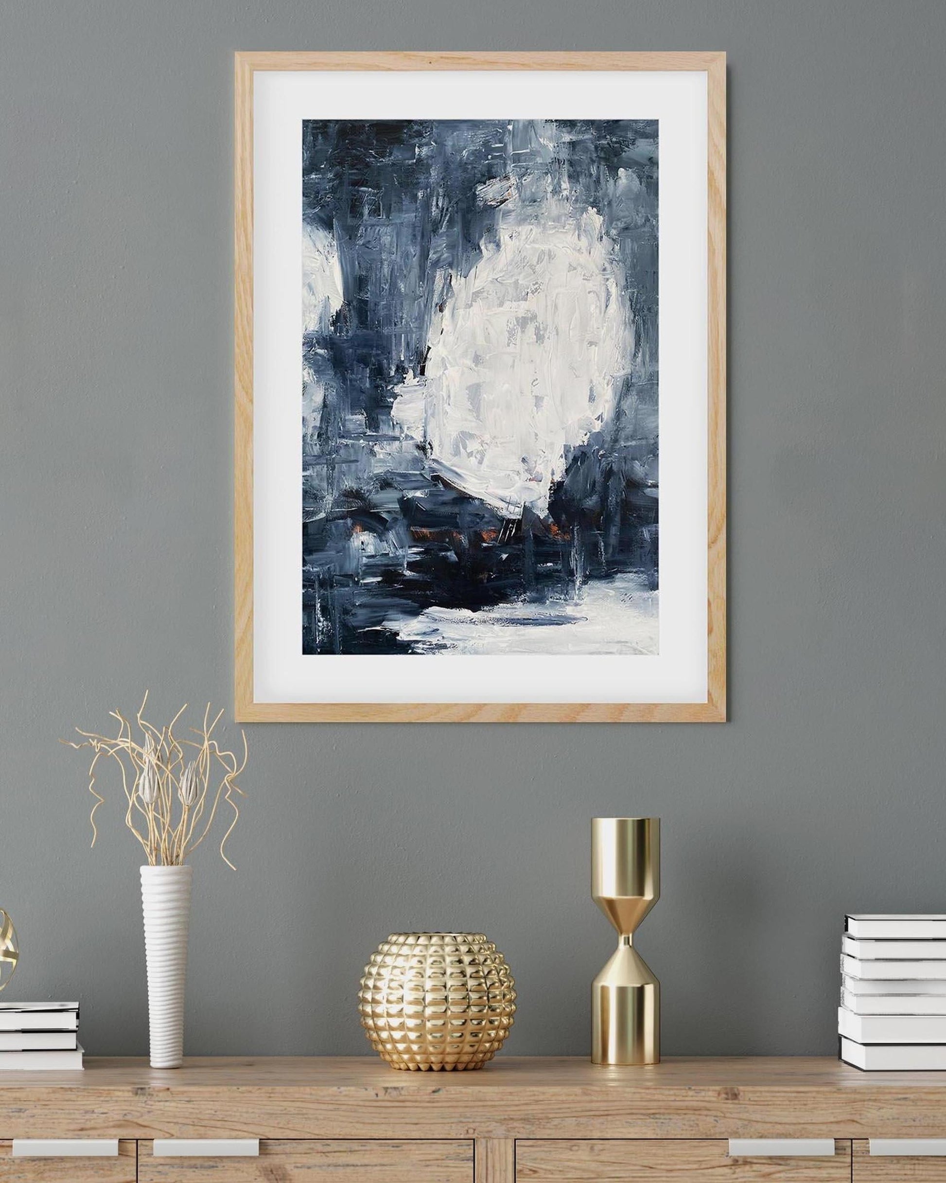 Framed abstract art on a gray wall with decorative items on a wooden console table.