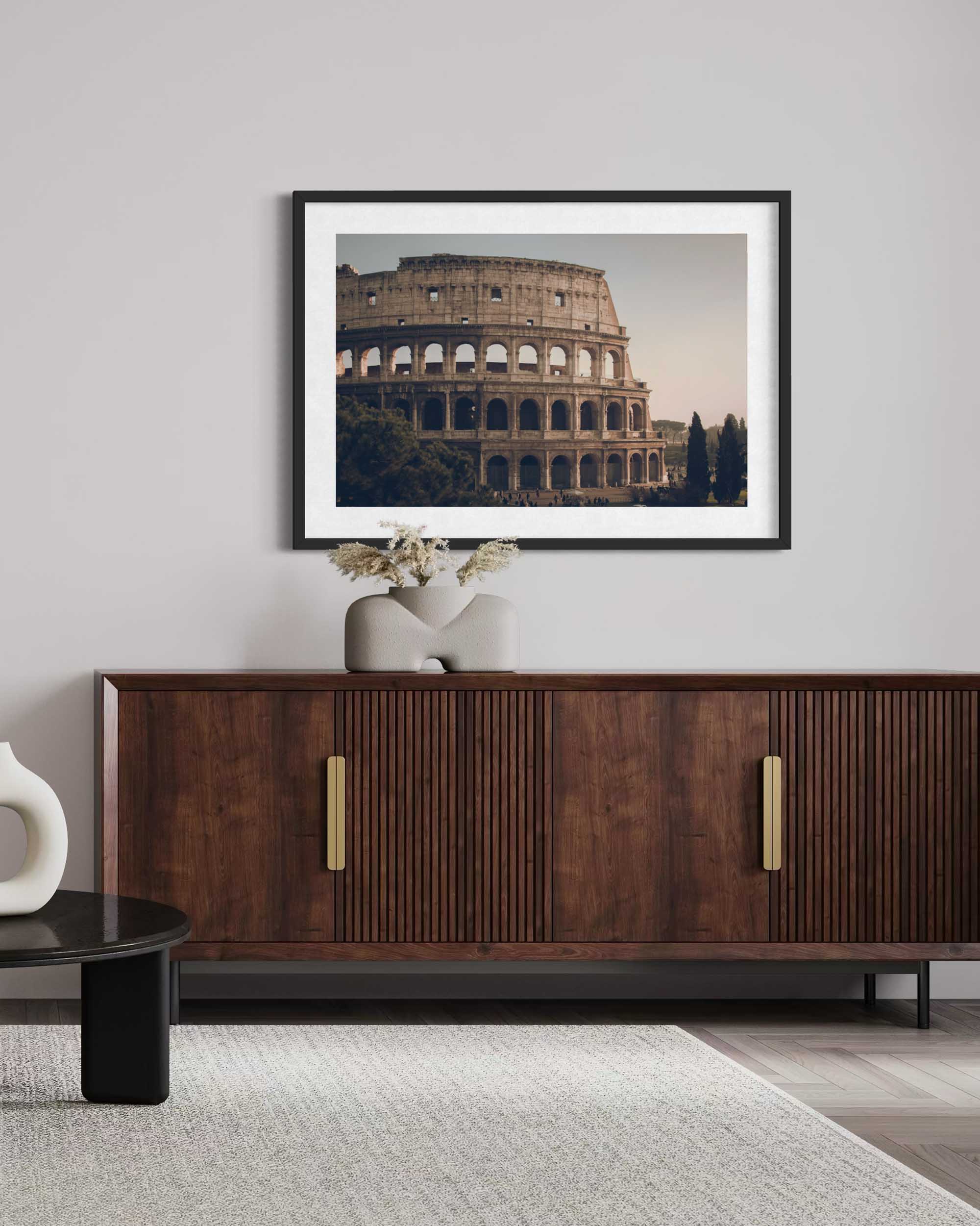Framed picture of the Colosseum above a wooden sideboard in a room.