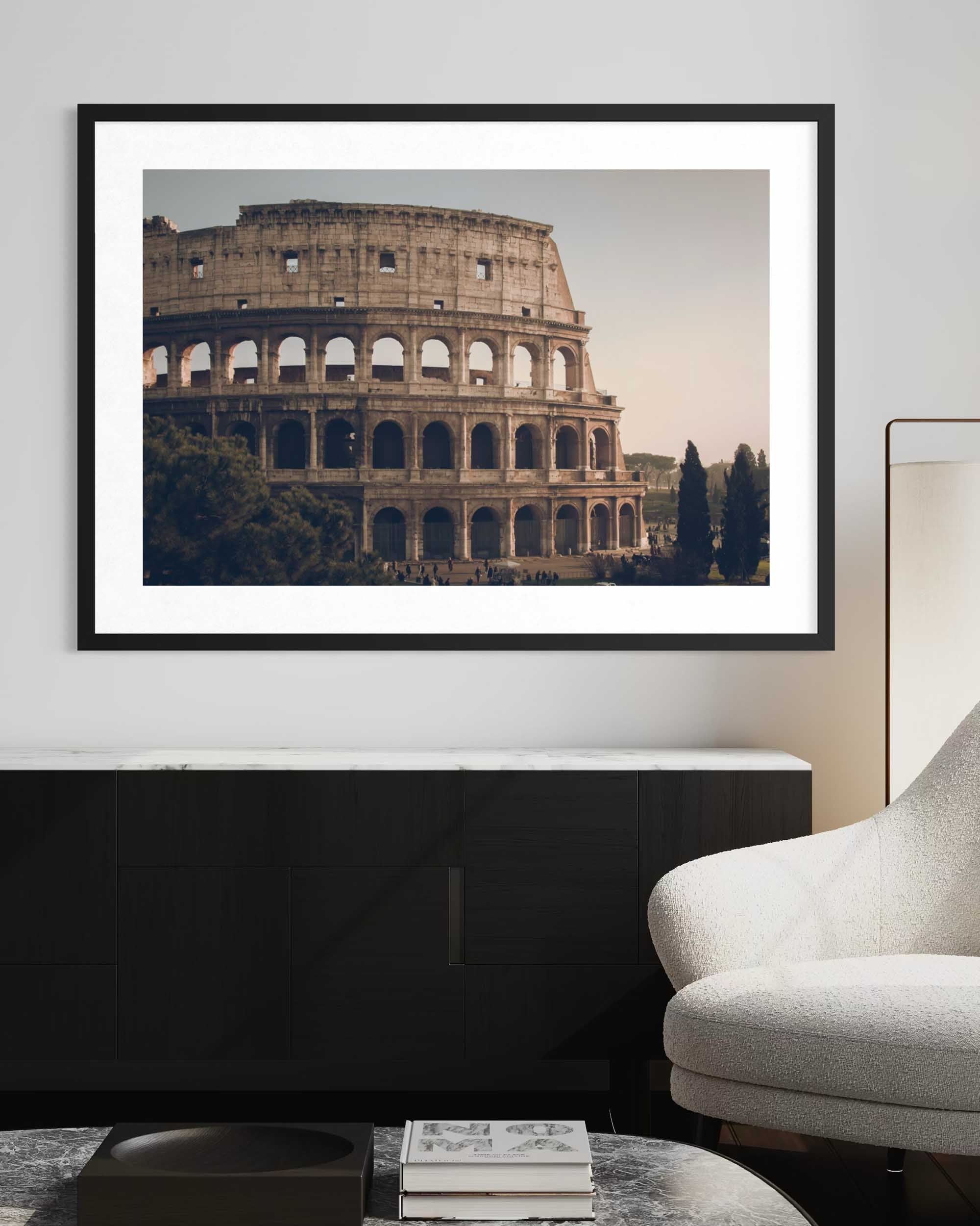 Framed photograph of the Colosseum in Rome on a wall above a black console table.