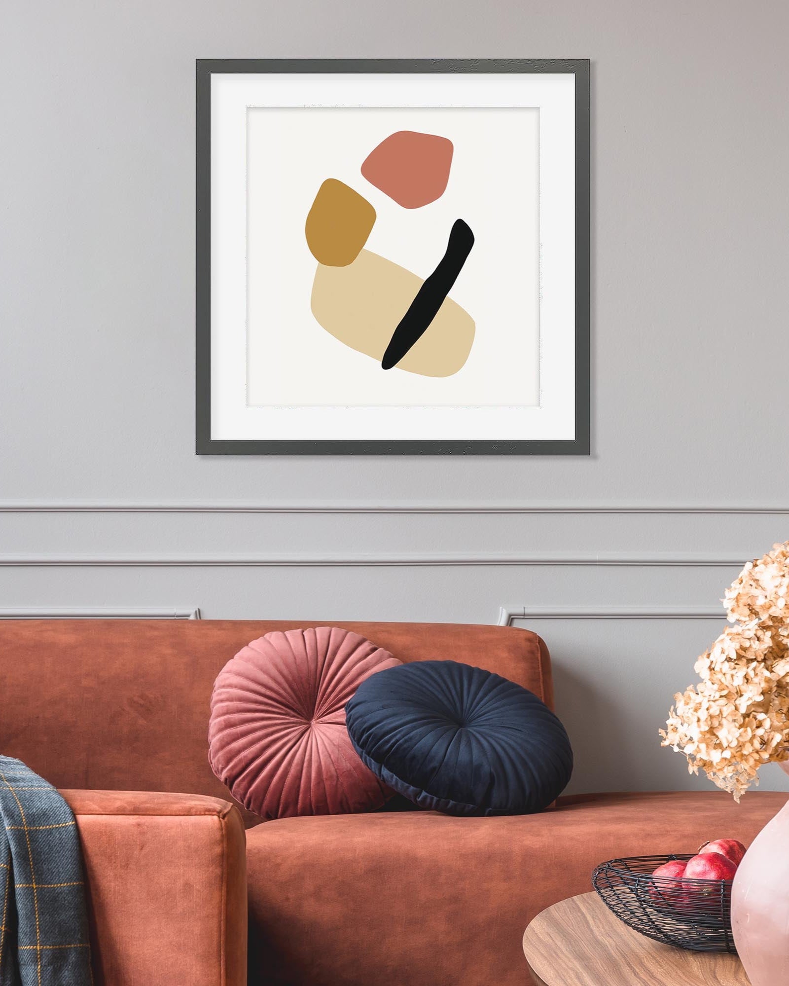 Framed abstract art piece on a wall above a sofa with decorative pillows.