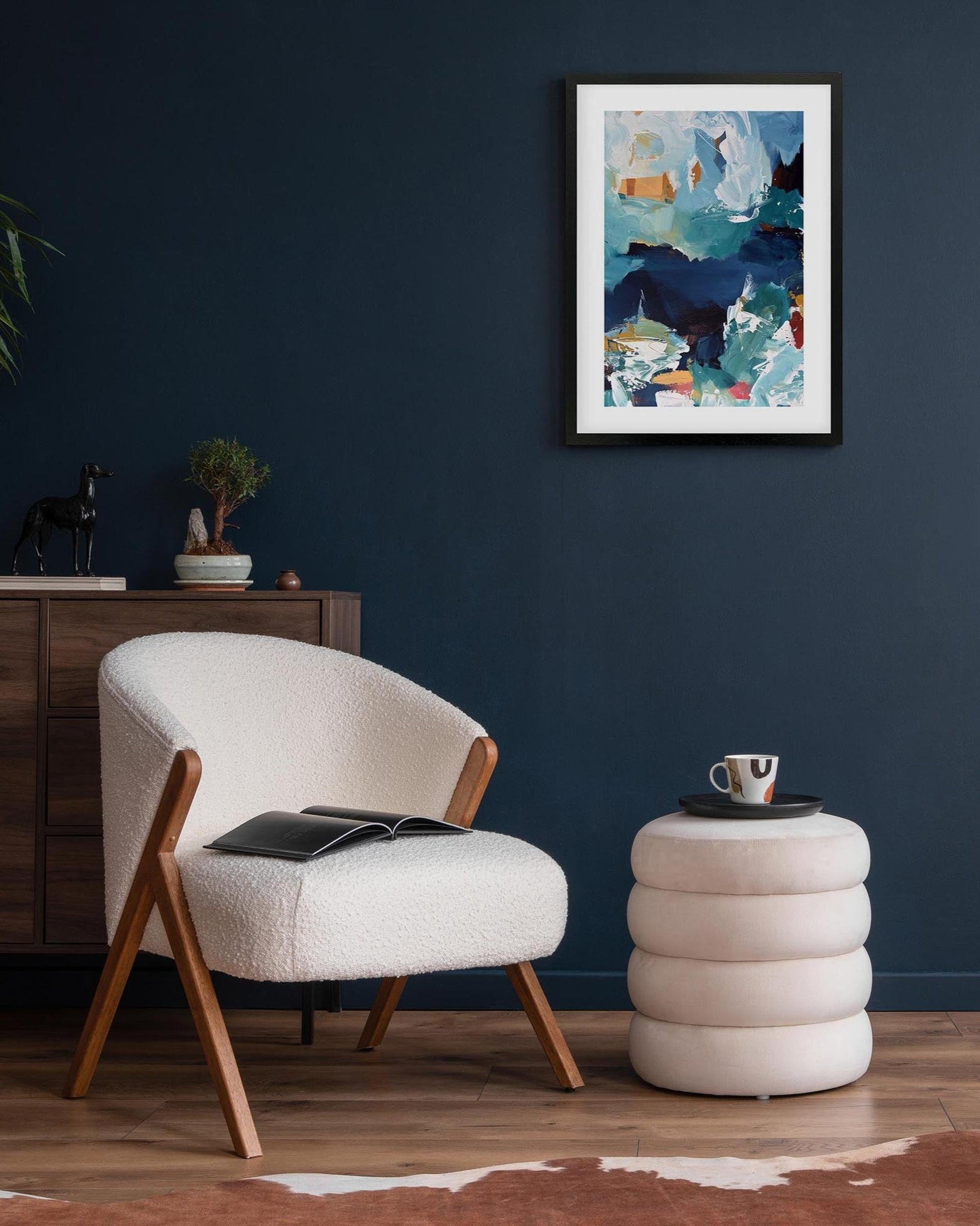 Modern living room with a white armchair, side table, and abstract art on the wall.