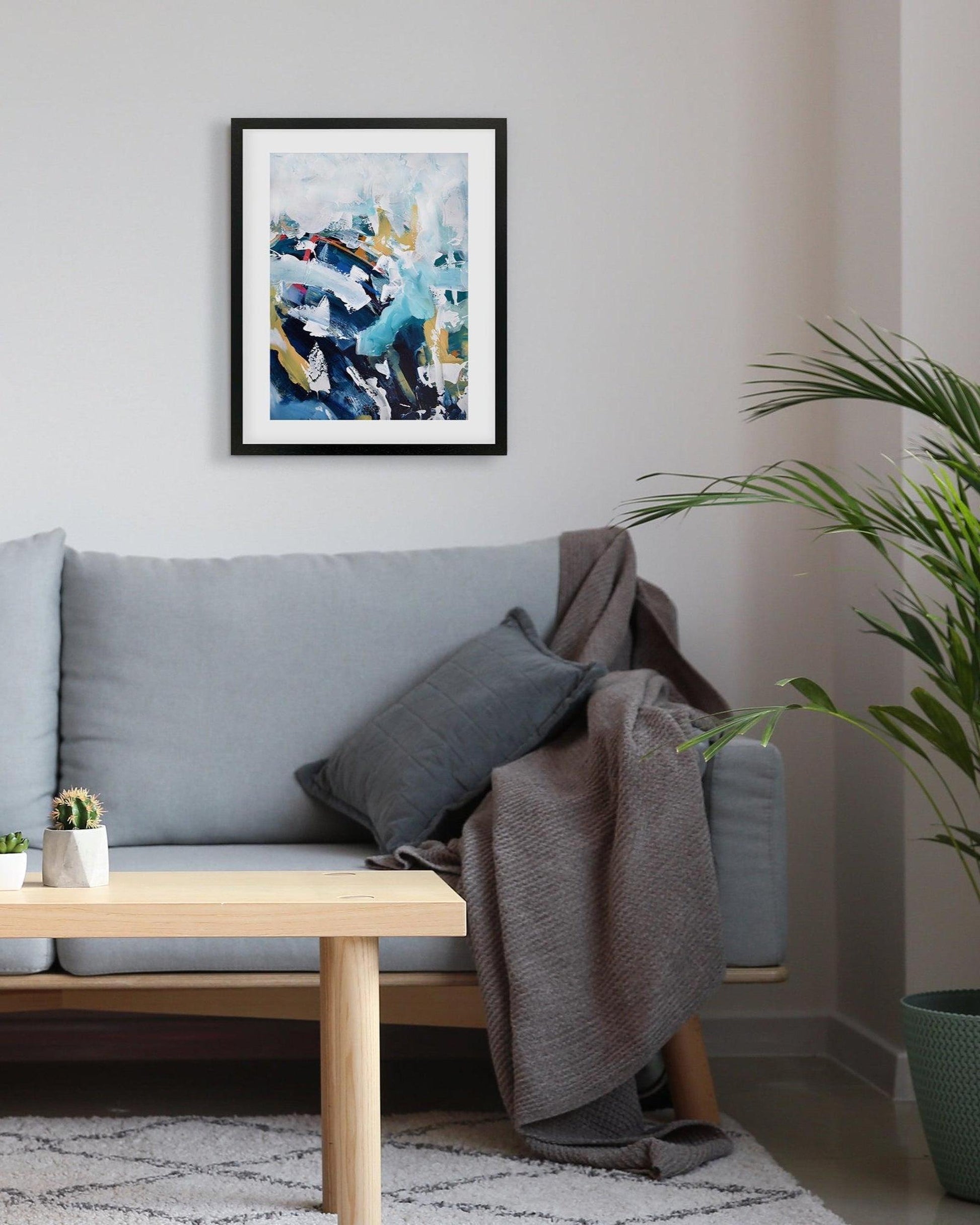 Living room with a gray sofa, wooden coffee table, and abstract art on the wall.