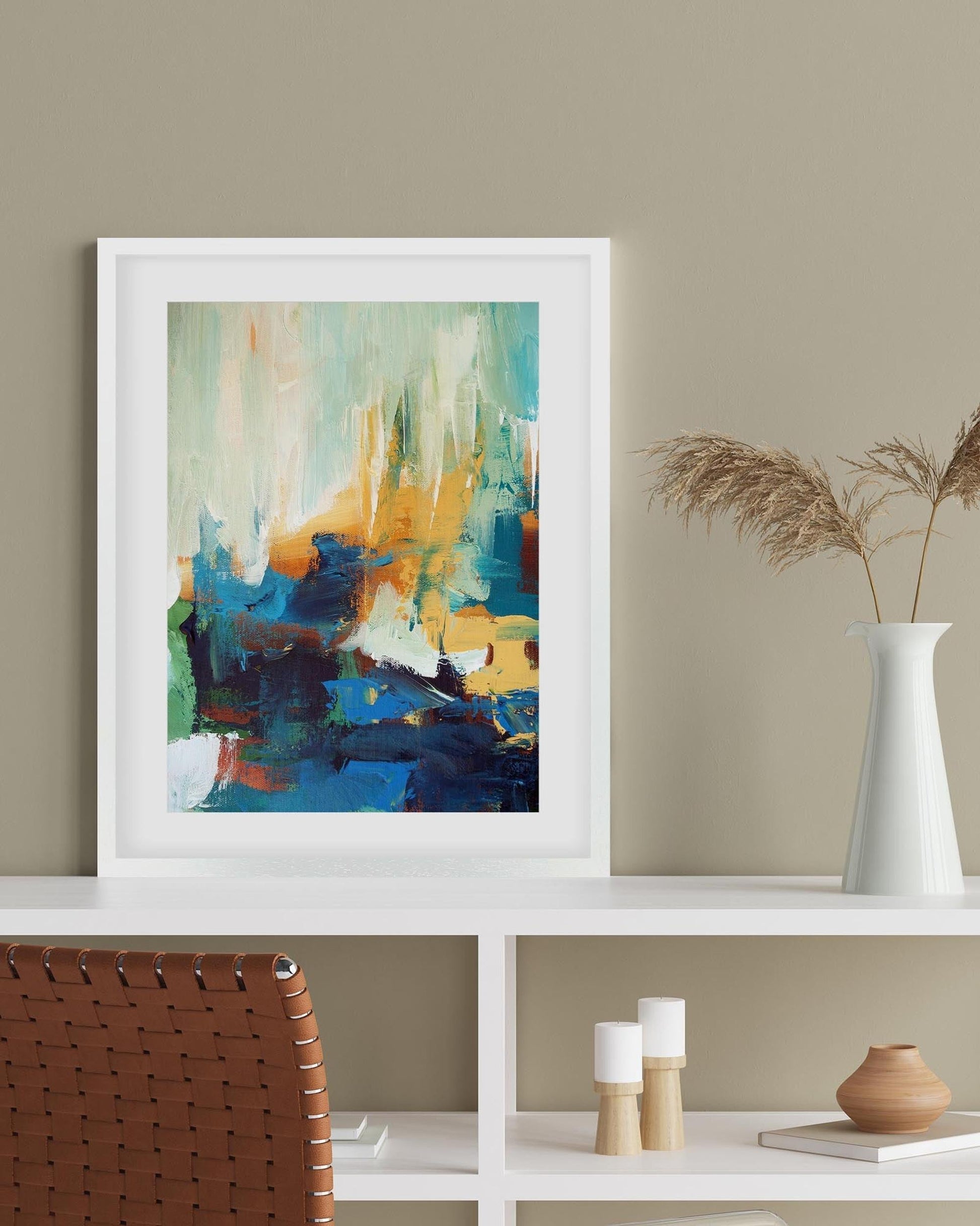 Framed abstract painting on a white shelf with decorative items against a beige wall.