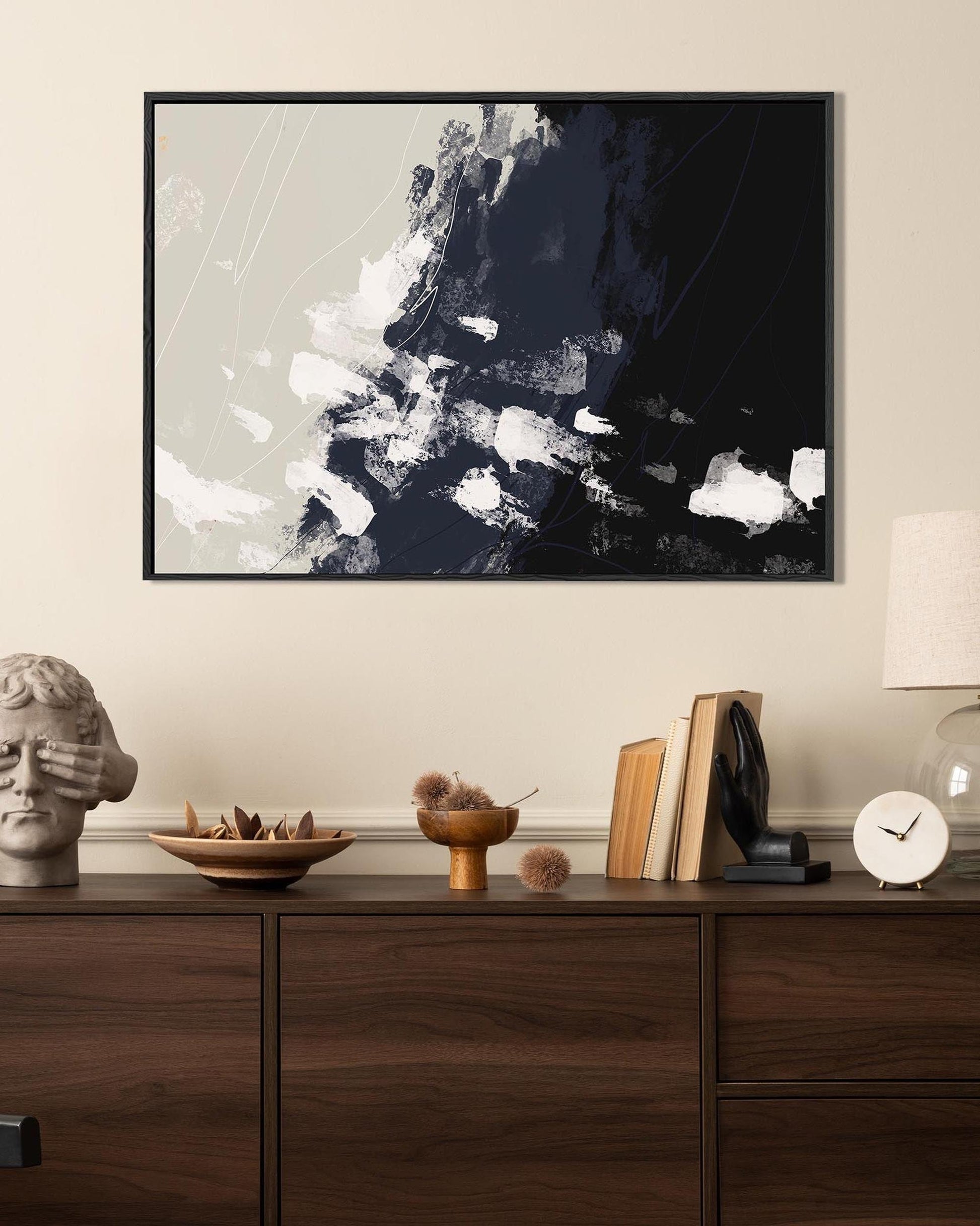 Abstract art piece on a wall above a wooden console table with decorative items.