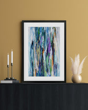 Framed abstract art piece on a black cabinet against a beige wall