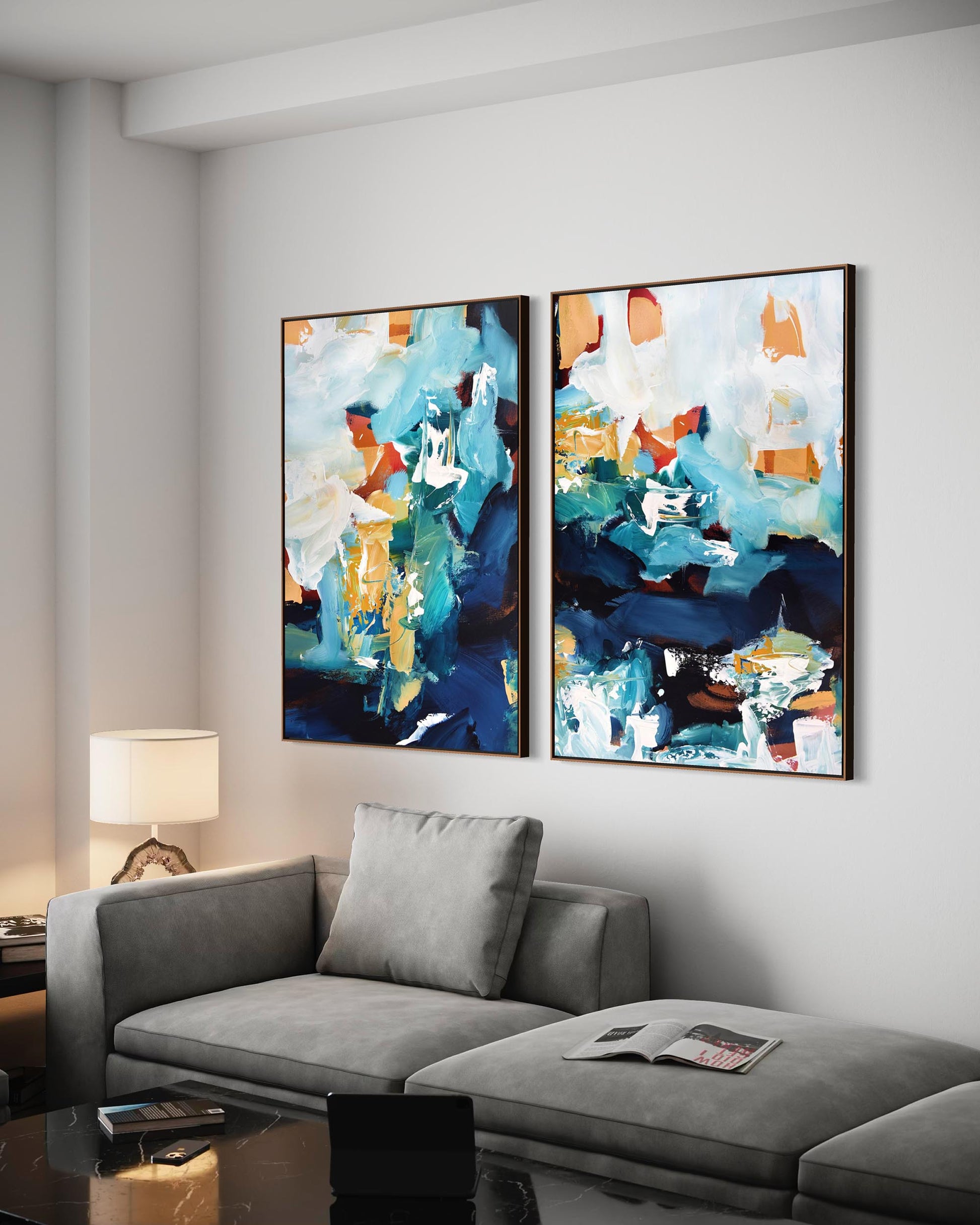 Two abstract art pieces on a wall above a gray sofa in a living room.