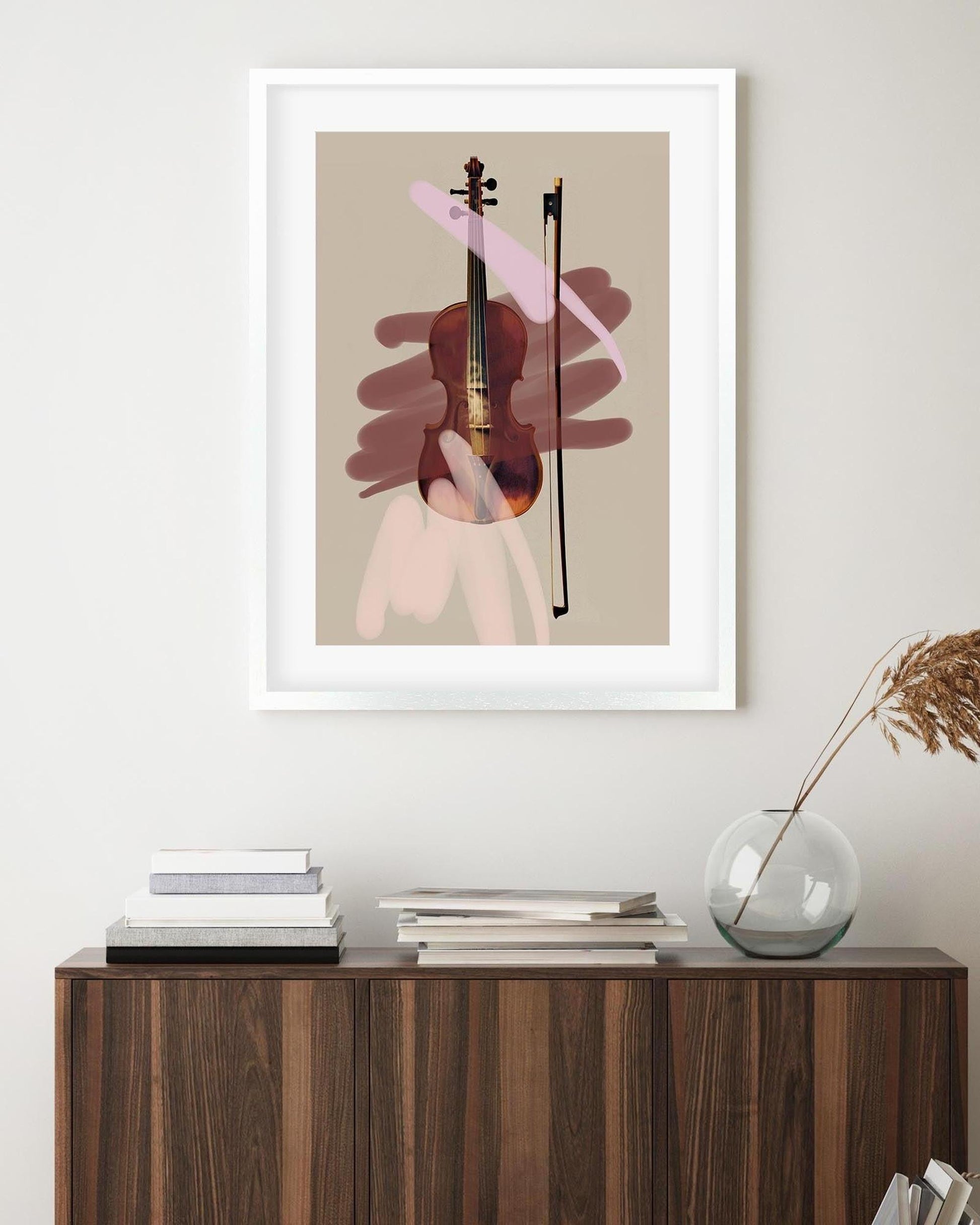 Framed abstract art print of a violin on a beige background, displayed above a wooden console table.