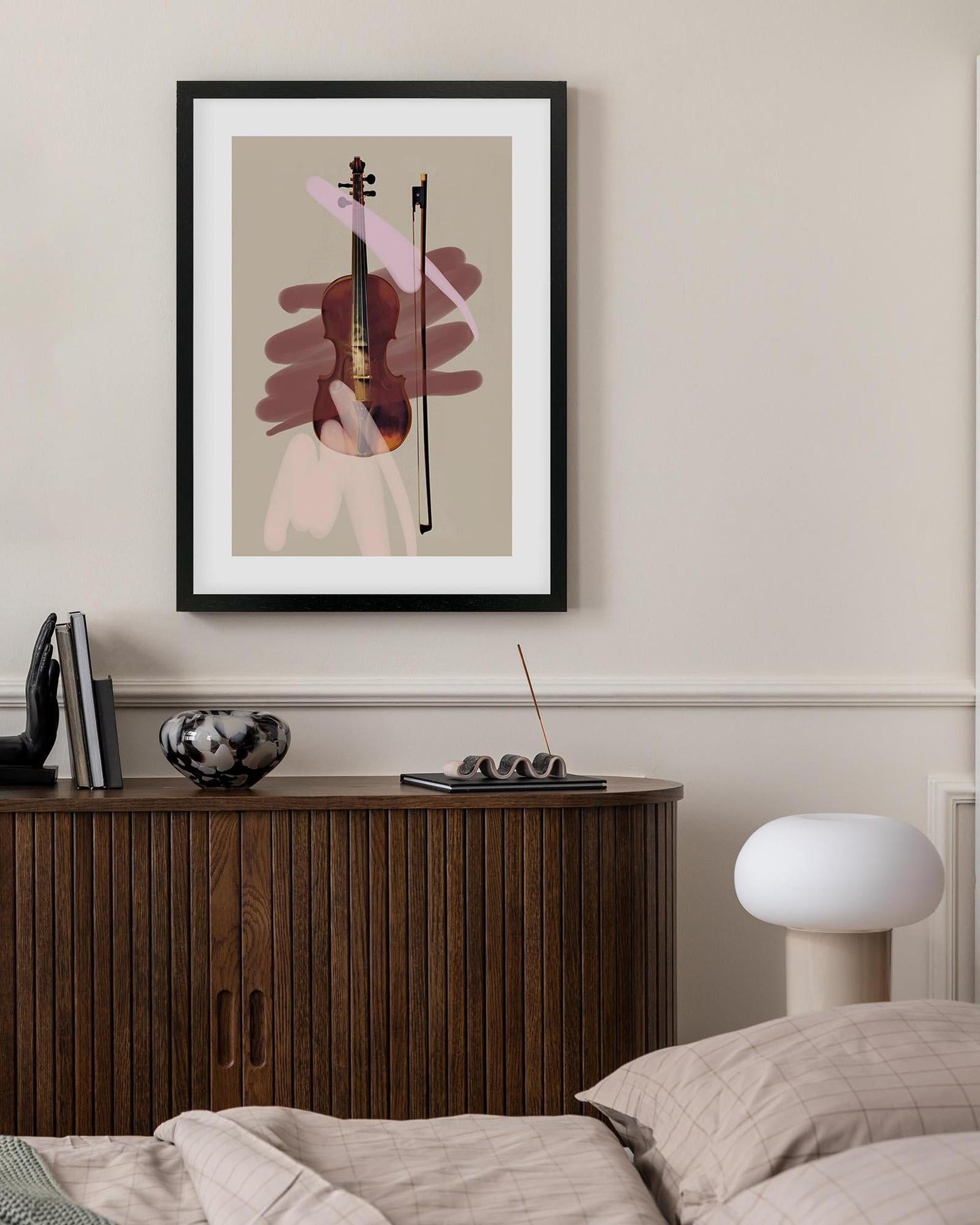 Framed abstract art of a violin on a wall above a wooden cabinet.