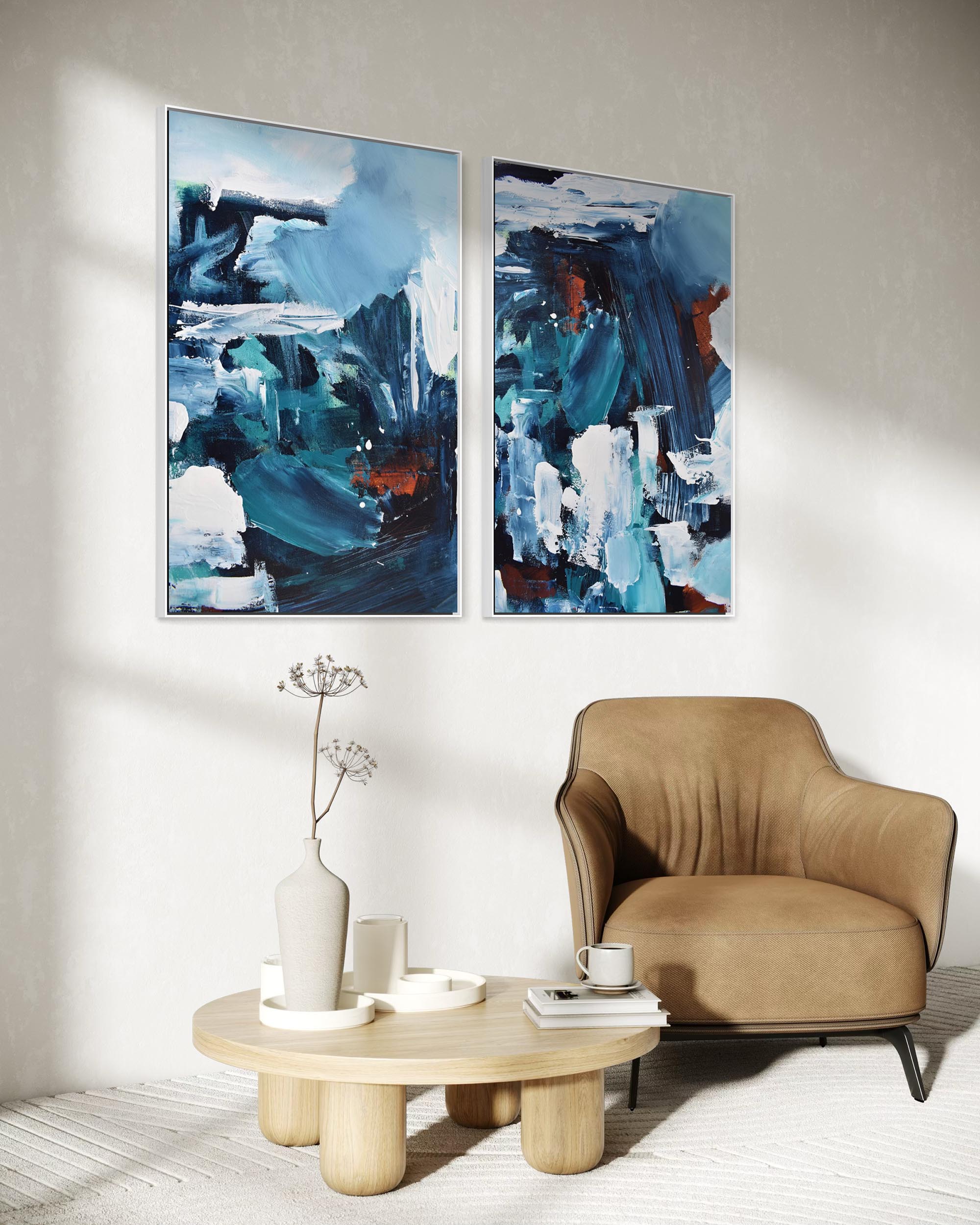 Two abstract paintings above a beige armchair and wooden coffee table in a living room.