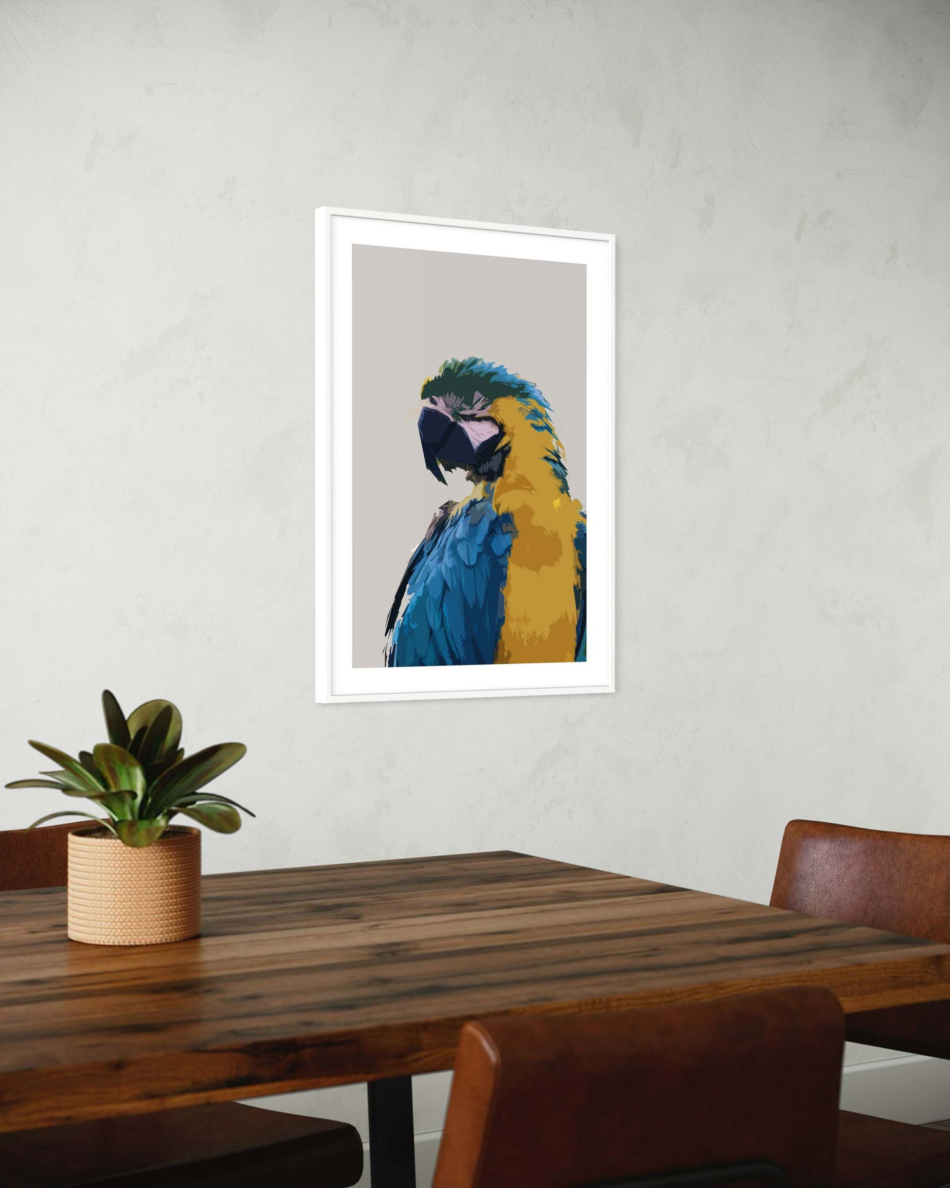 Framed artwork of a parrot on a wall above a wooden table with a plant.