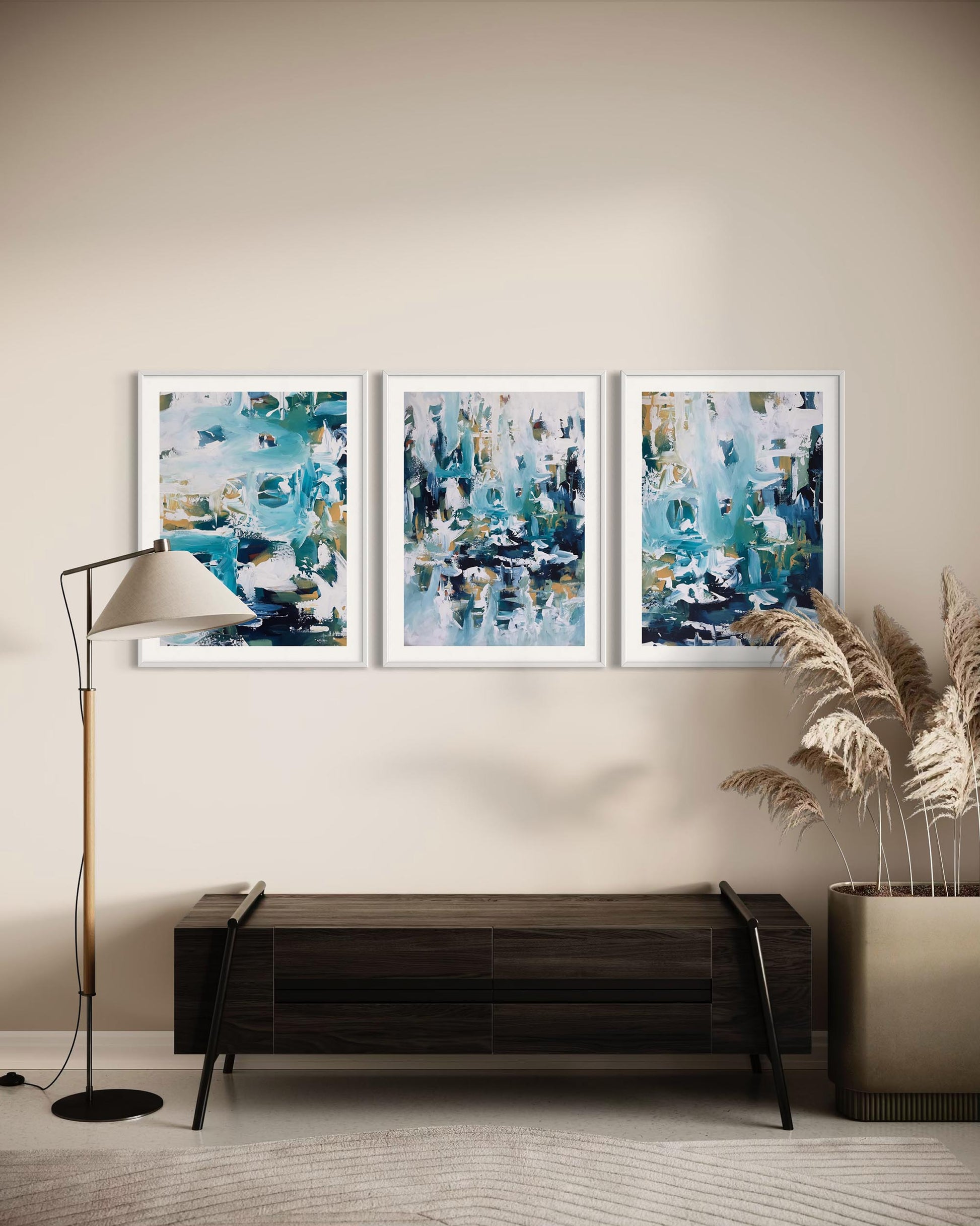Three abstract paintings on a wall above a wooden console table.