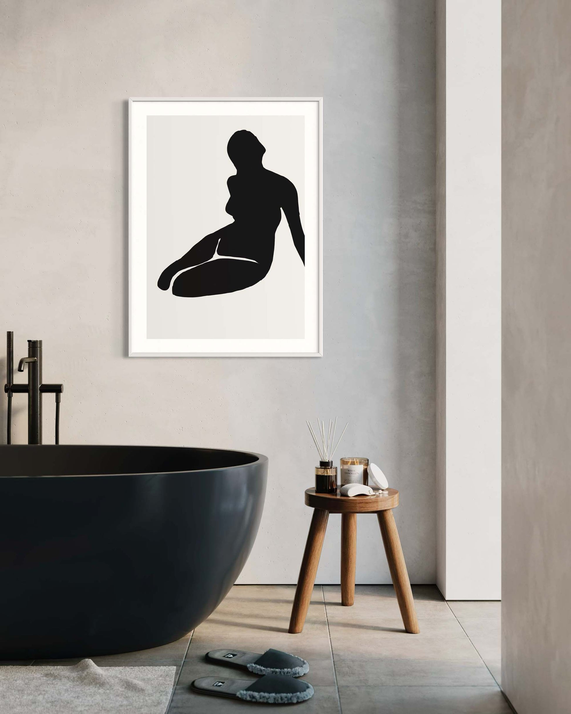 Framed black silhouette art print of a woman sitting on a wall in a modern bathroom.