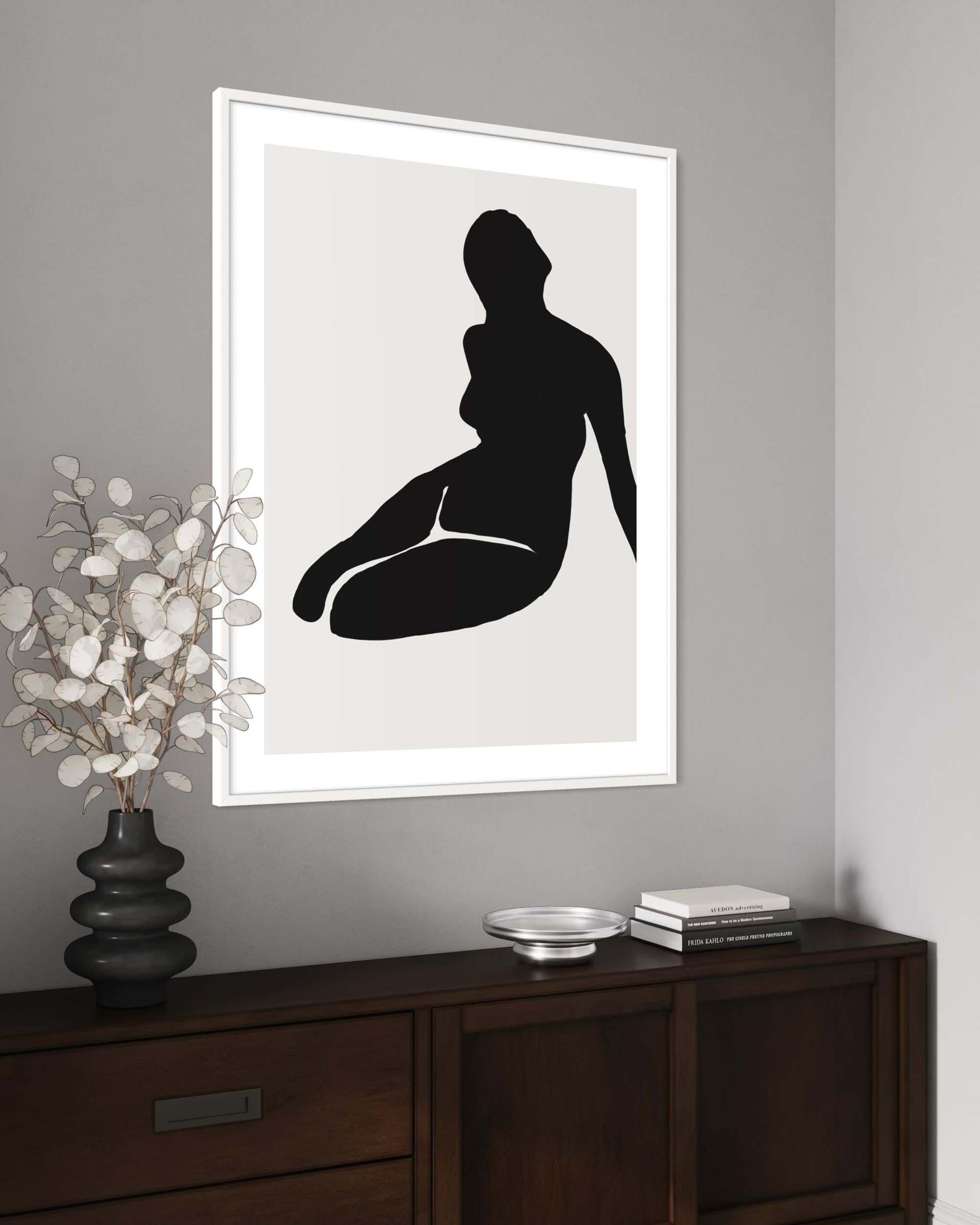 Framed black silhouette art on a gray wall above a wooden console table.
