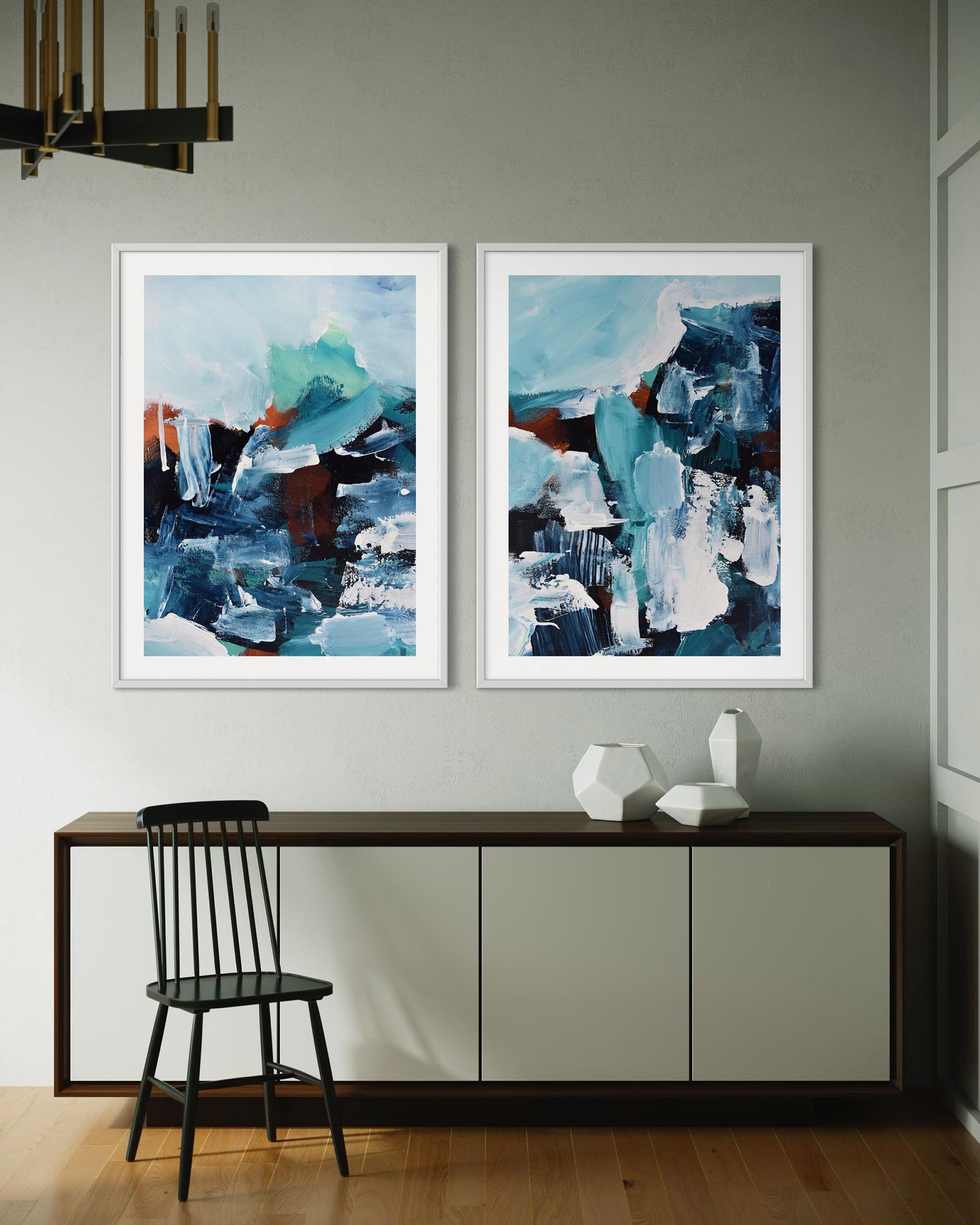 Two abstract paintings on a wall above a console table with a chair.