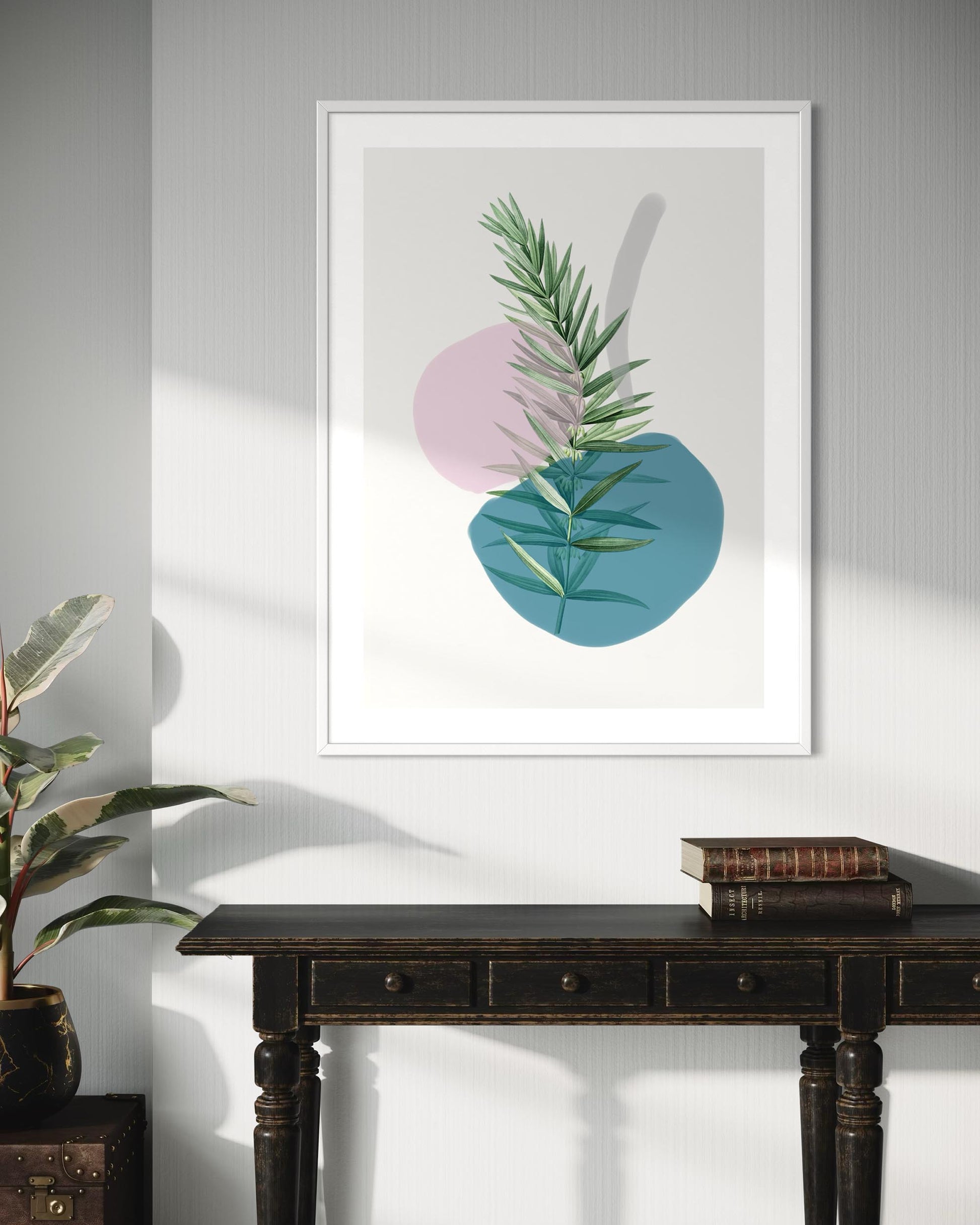 Framed artwork with abstract design of leaves and circles on a wall above a wooden table.