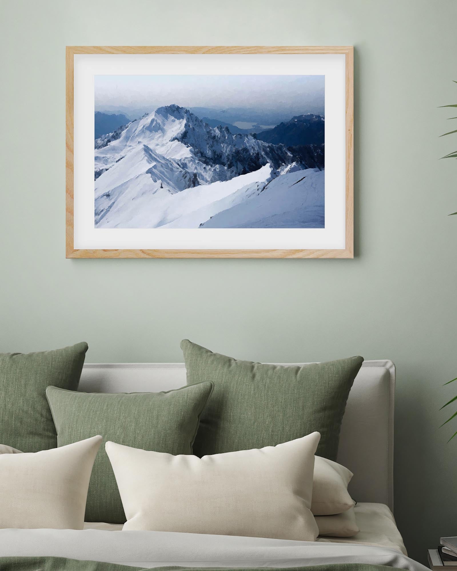 Framed mountain landscape print on a wall above a sofa with cushions.