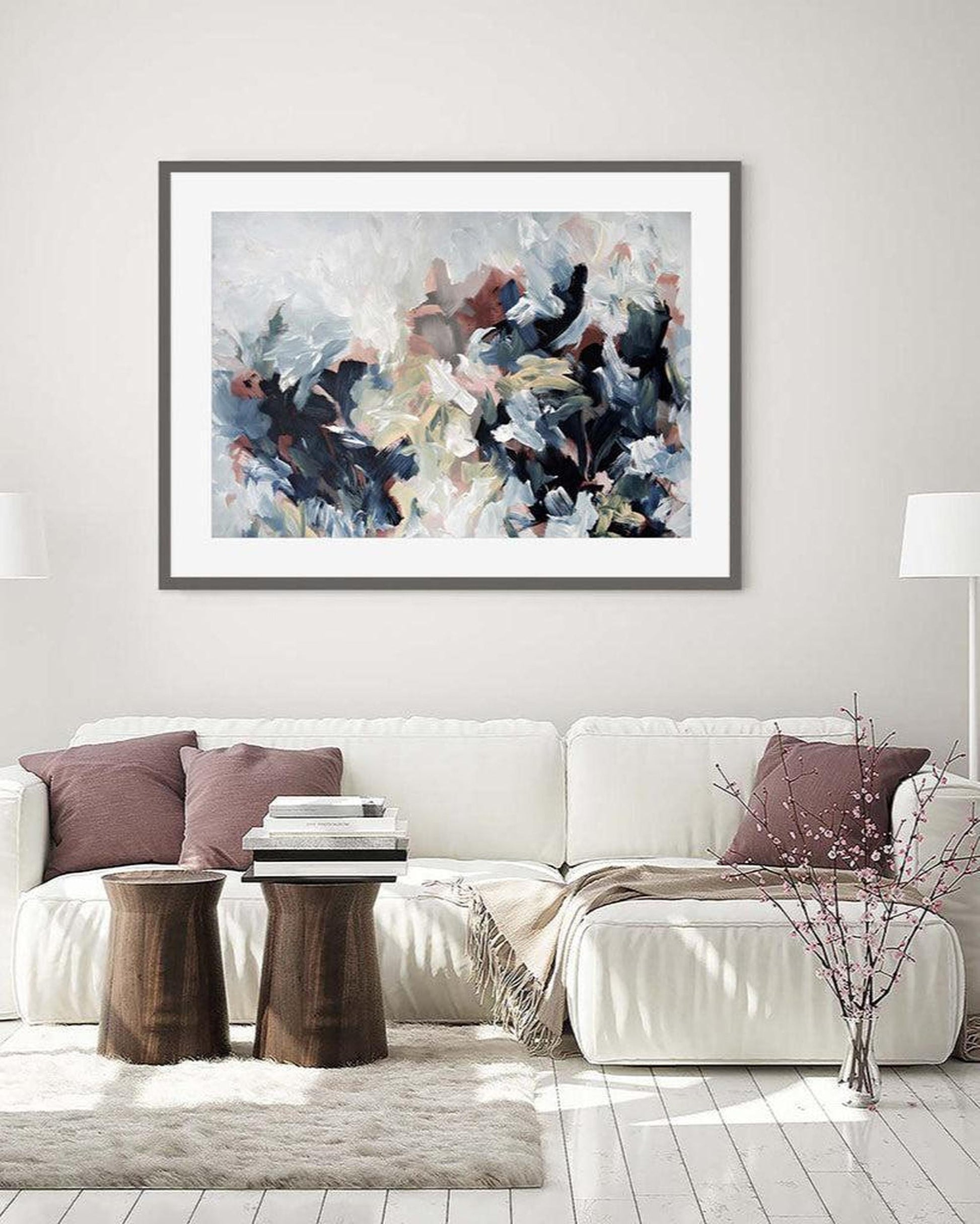 Abstract art print on a wall above a white sofa in a living room.