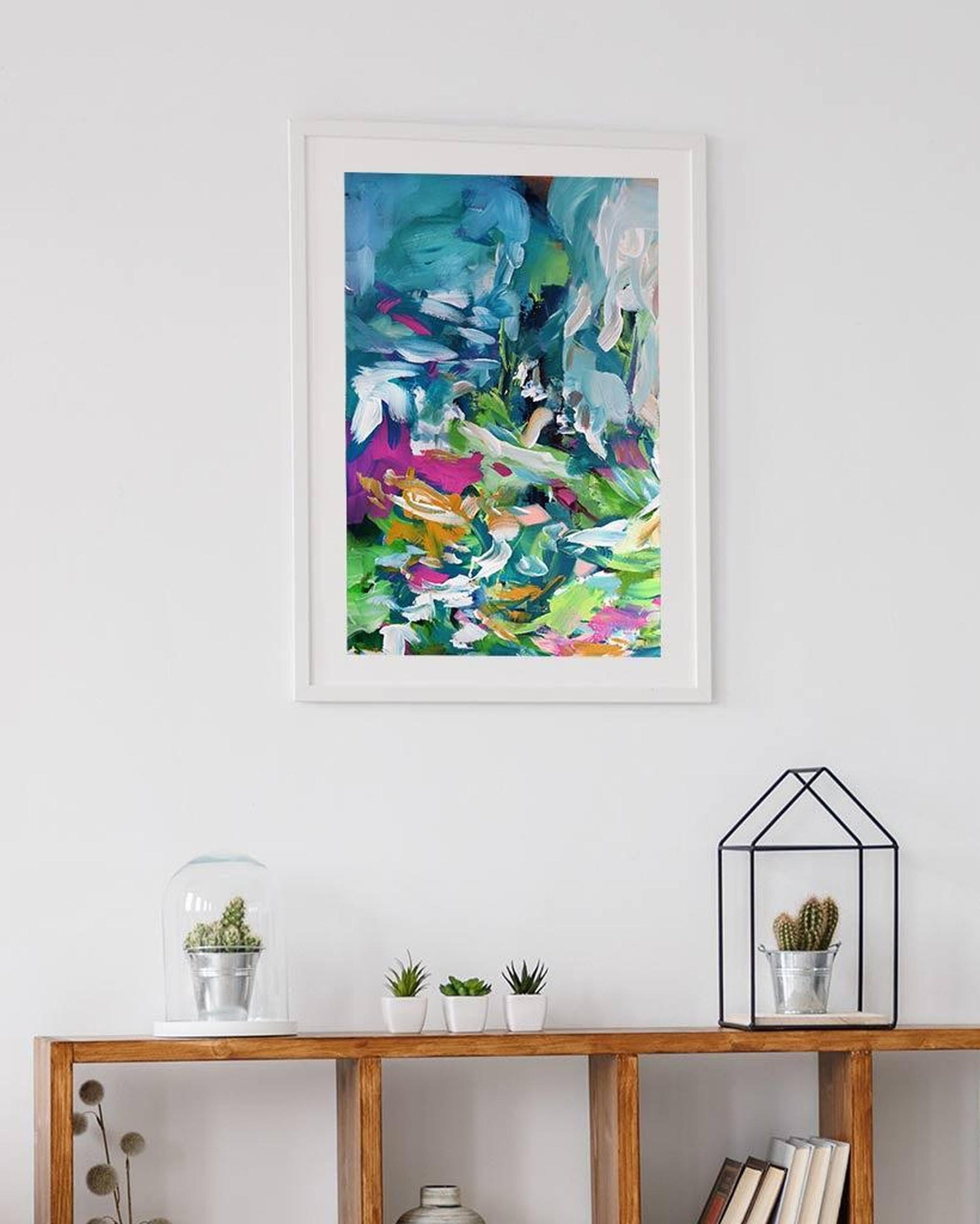 Colorful abstract art print on a white wall above a wooden console table with decorative items.