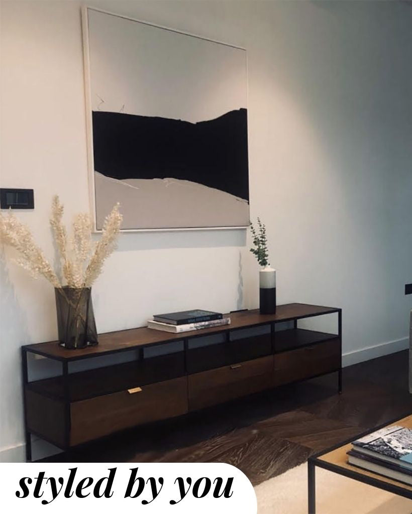 Modern living room with a wooden console table, decorative items, and a large mirror.