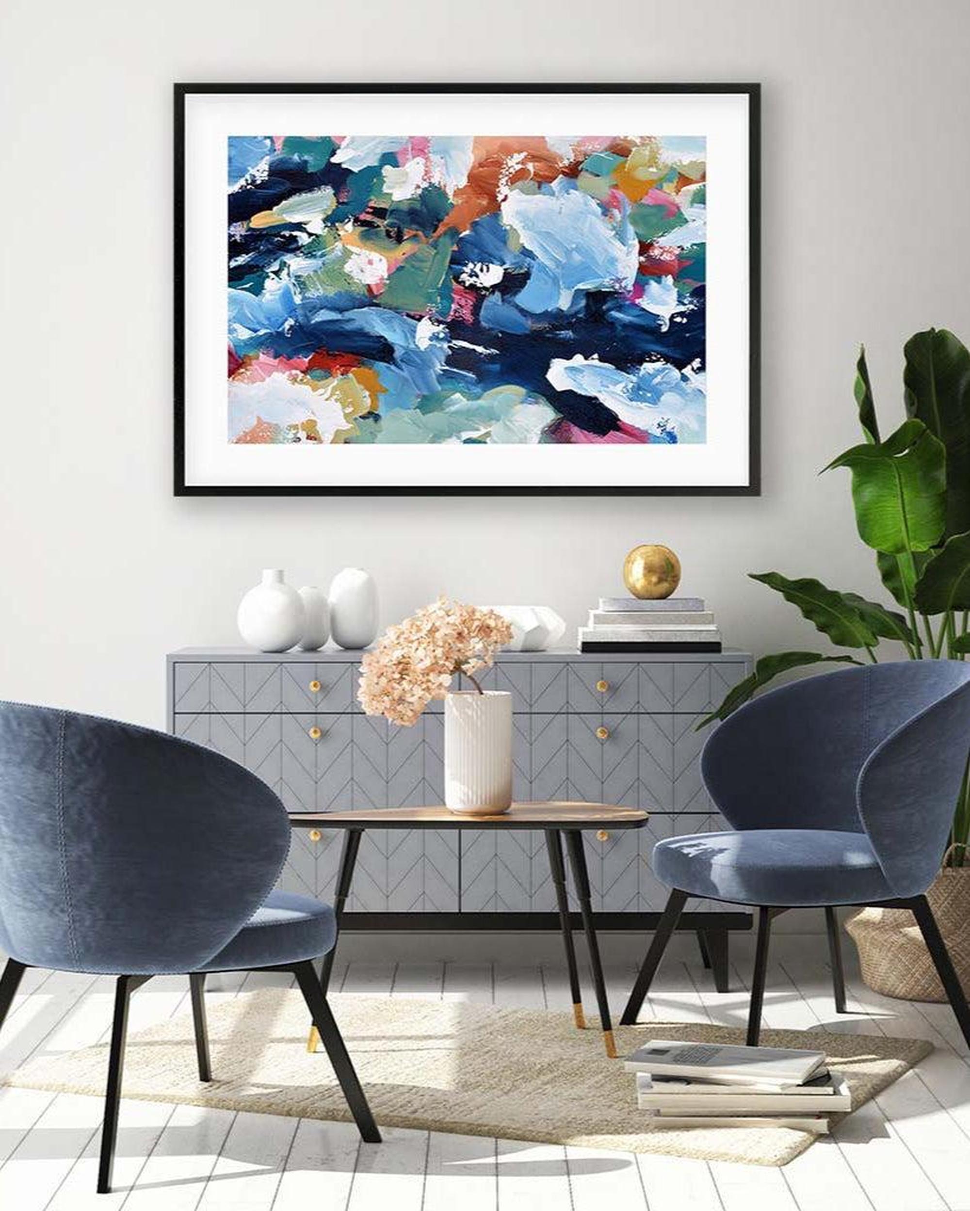 Modern living room with abstract art, blue chairs, and a side table.